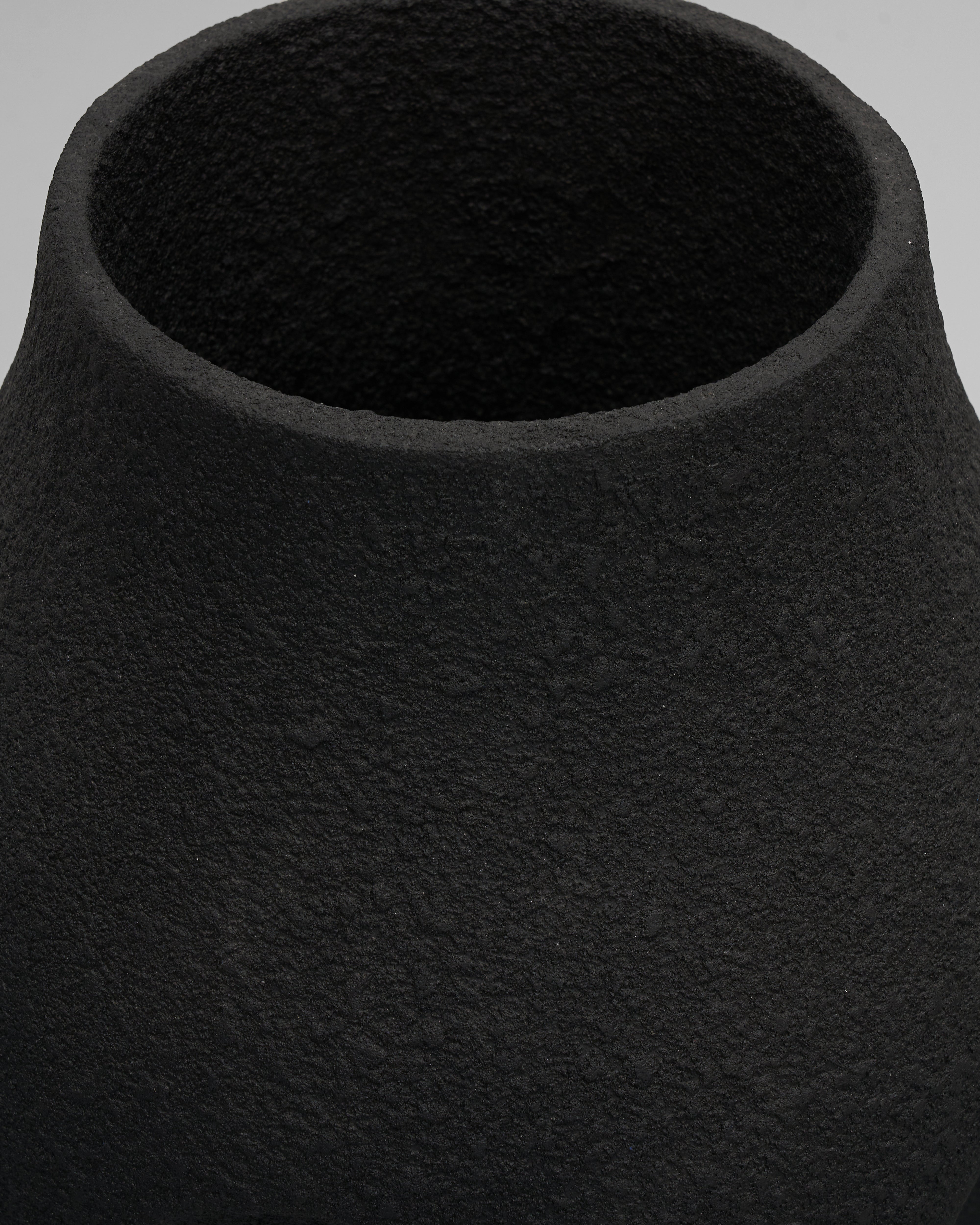 Close-up of a textured black vase on a light gray background