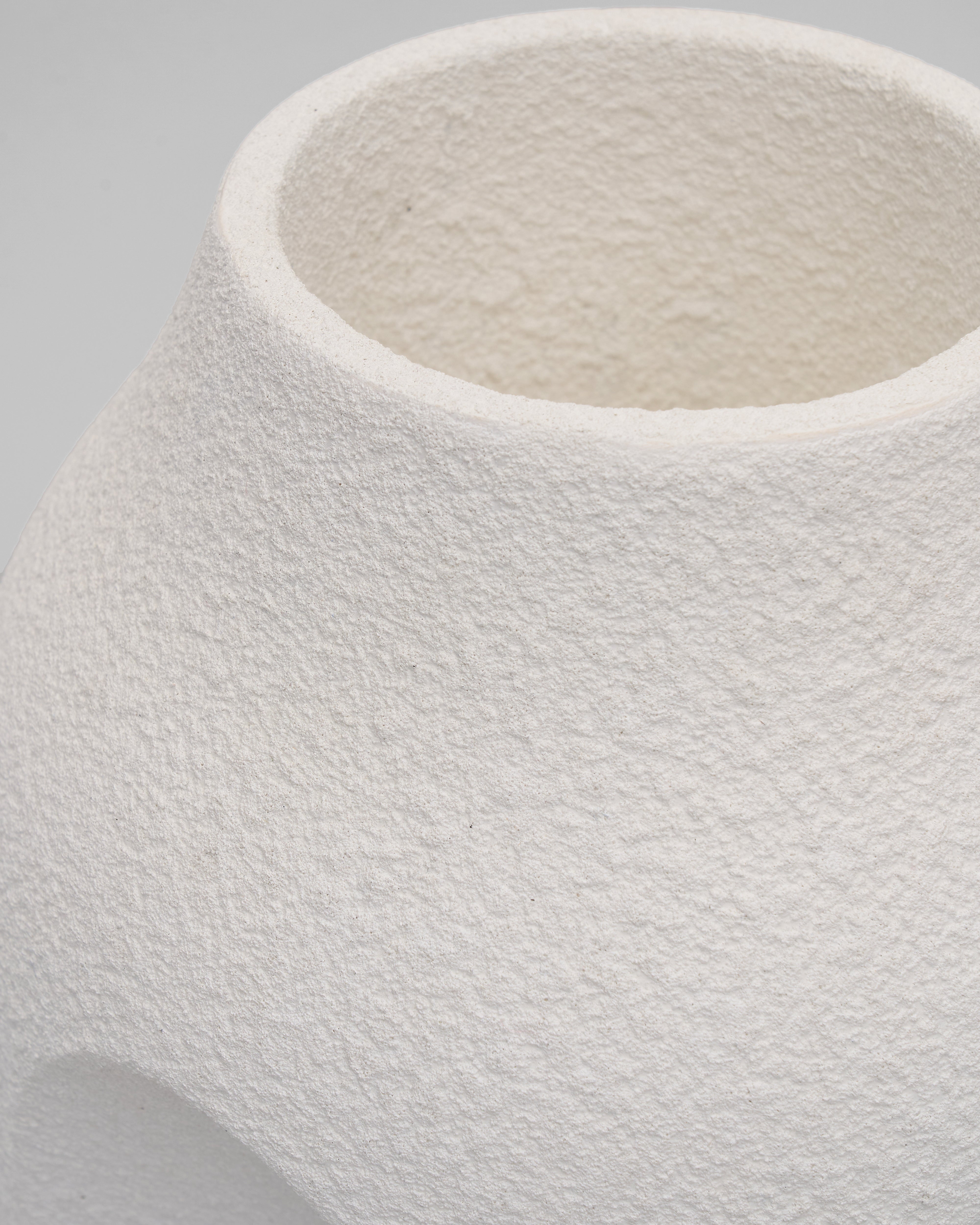 Close-up of a textured white ceramic vase on a gray background