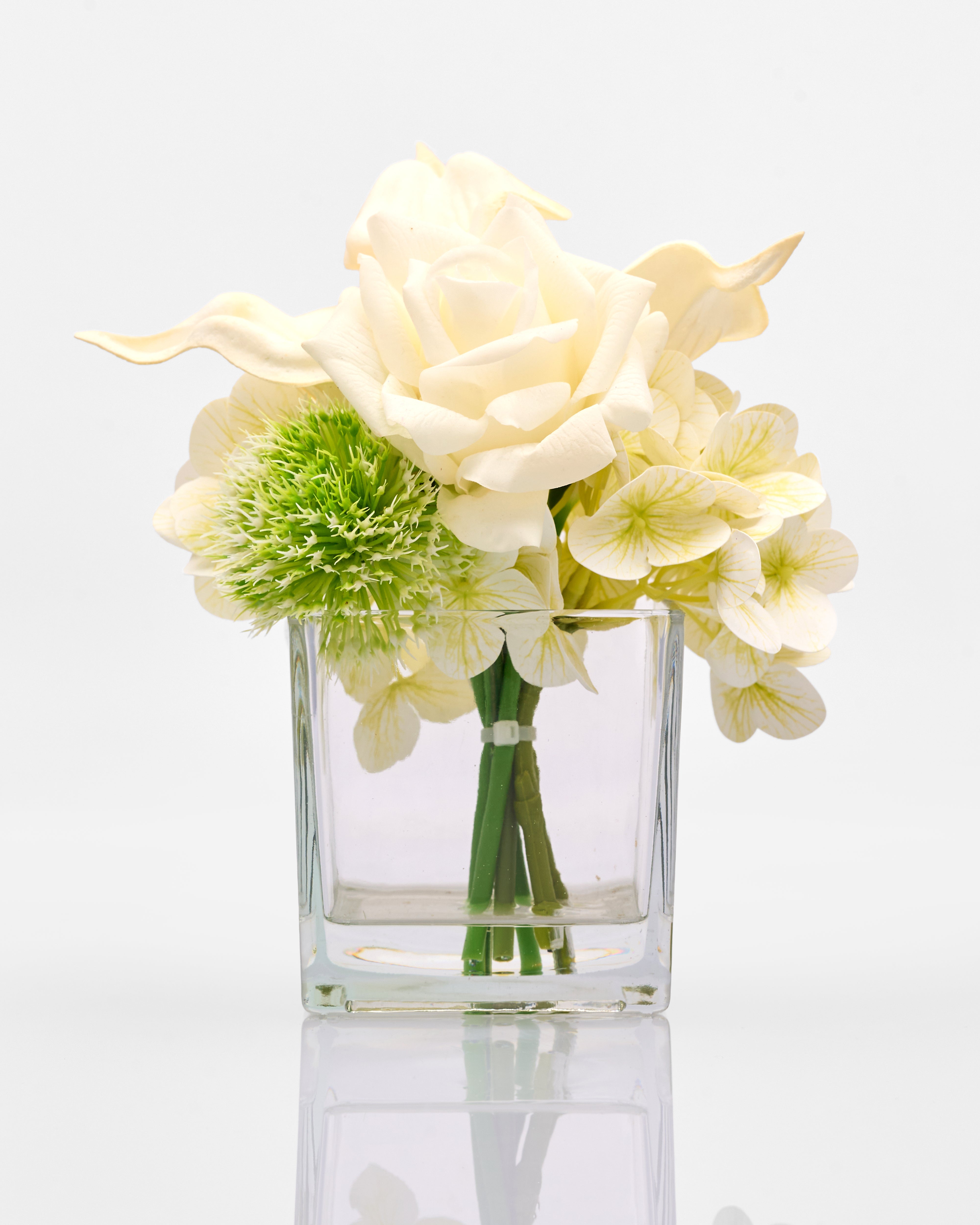 Clear glass vase with white and green flowers on a light gray background