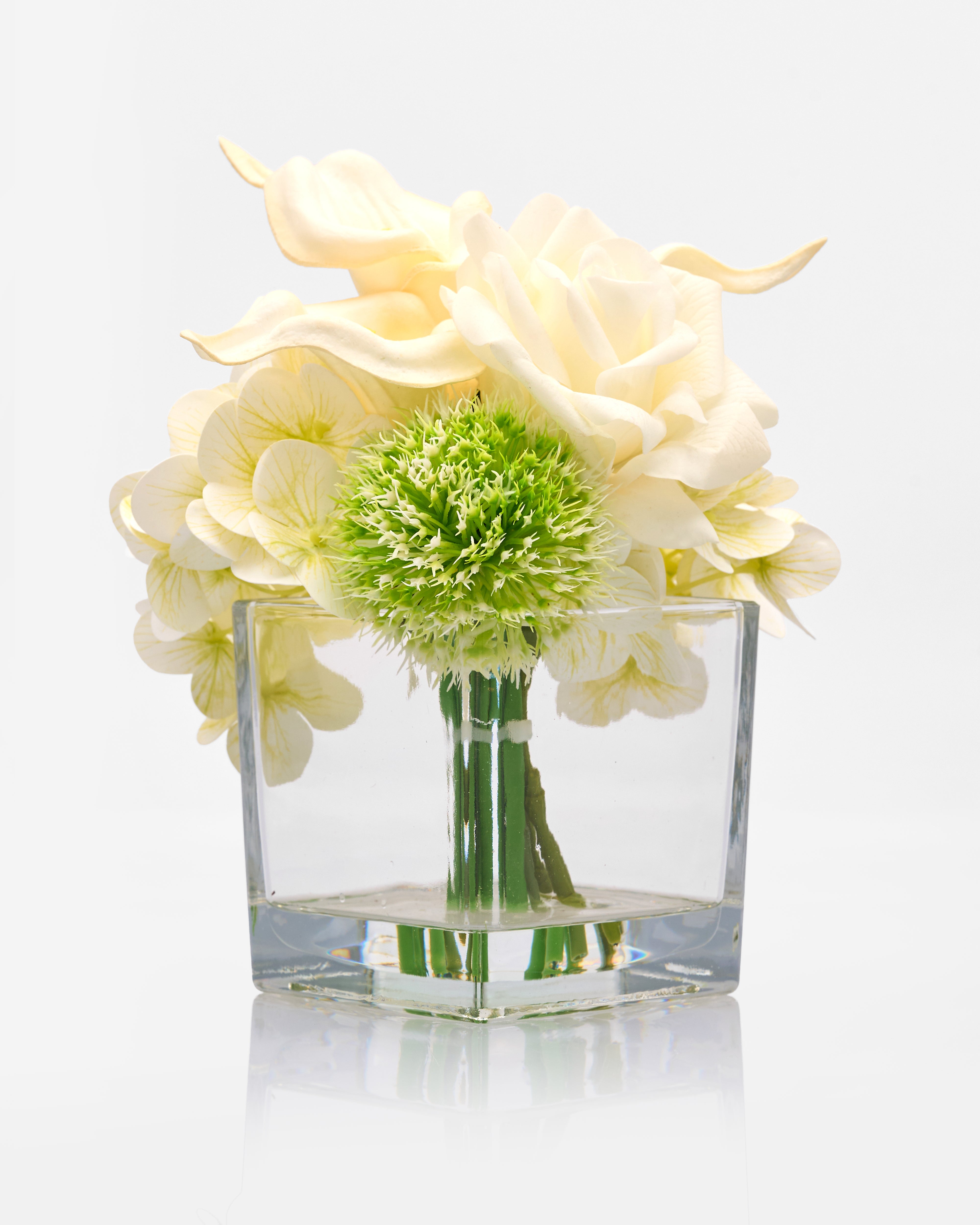 Clear glass vase with white and green flowers on a light gray background
