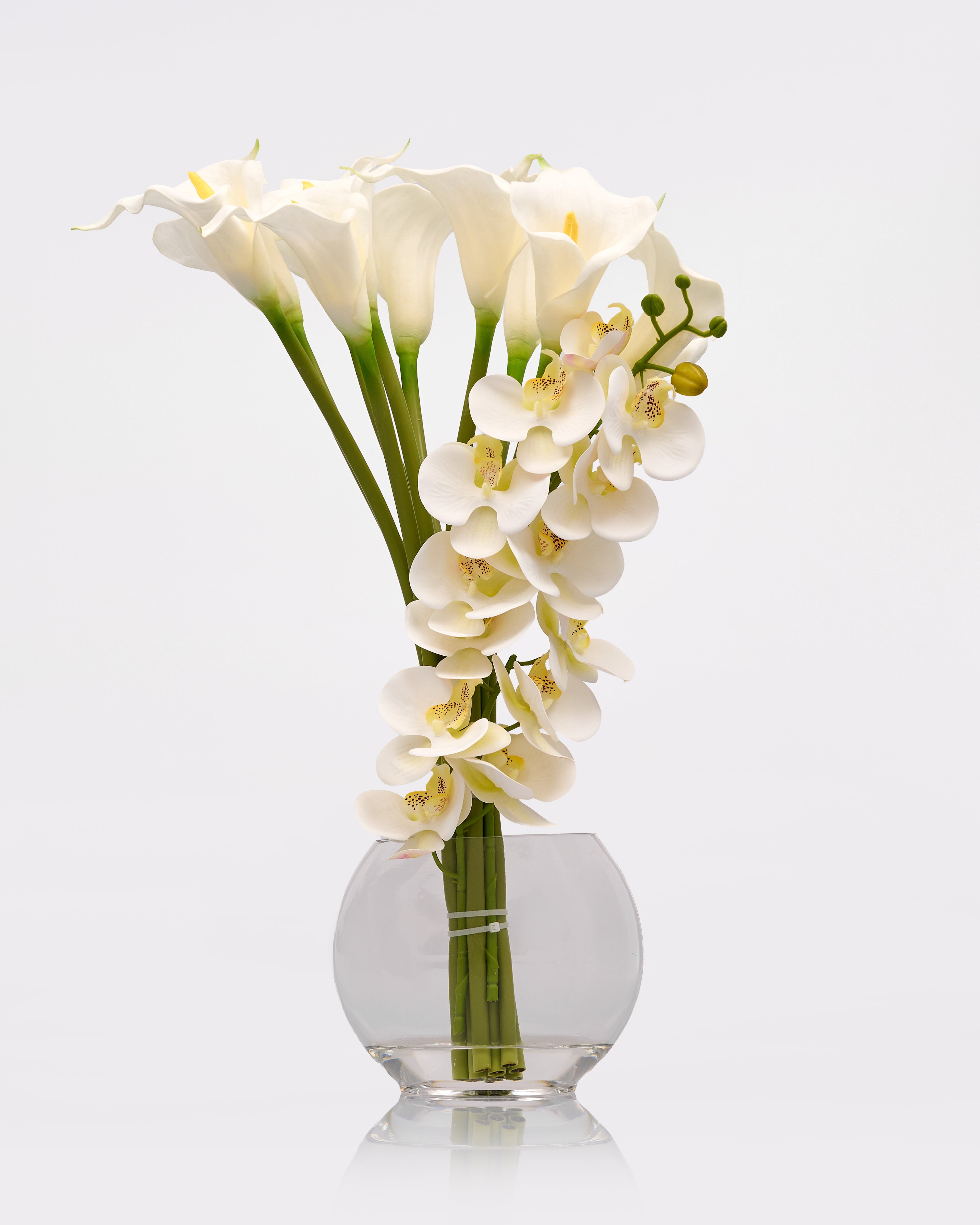 Clear glass vase with white flowers on a light gray background