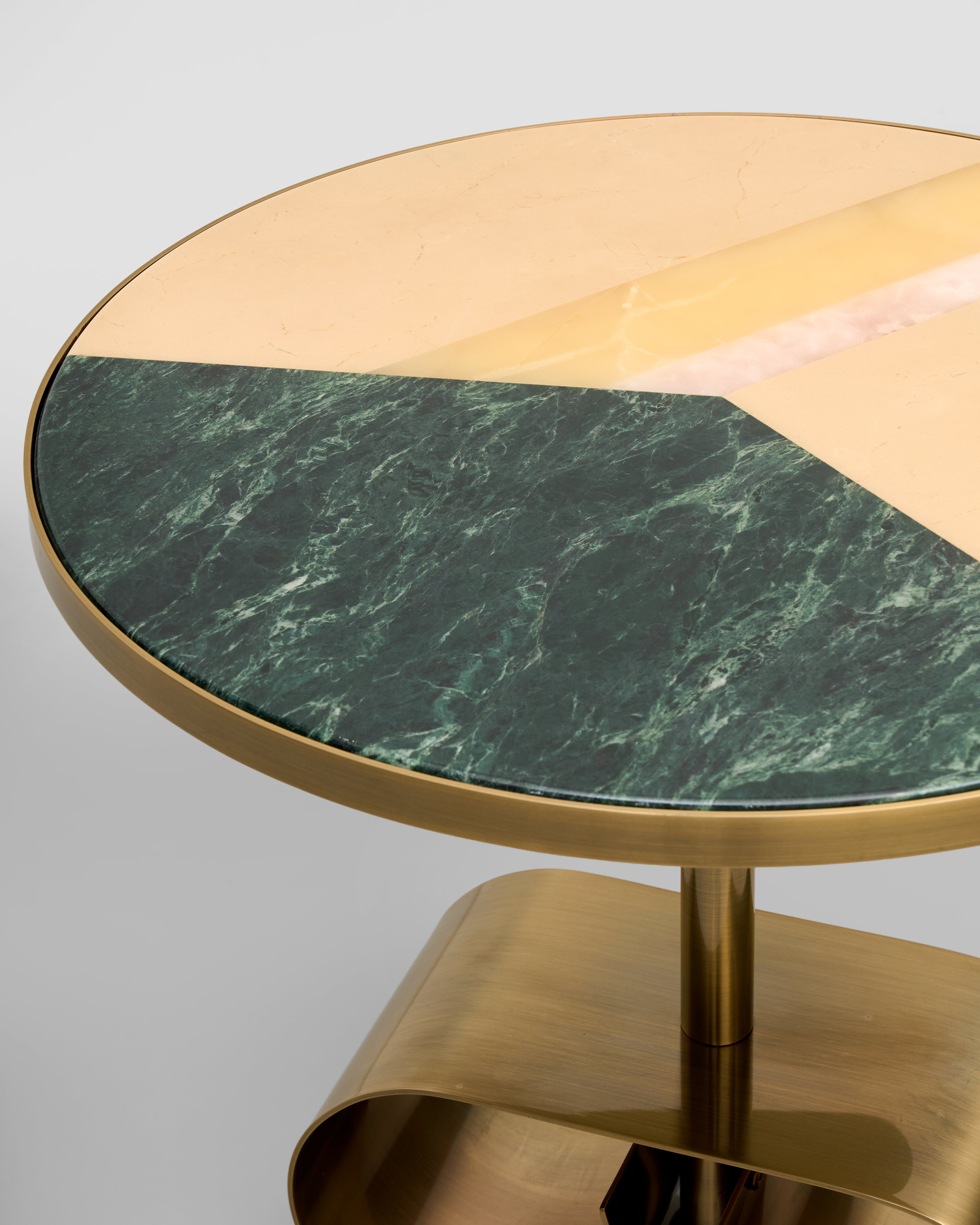 Round table with gold base and green marble top on a gray background