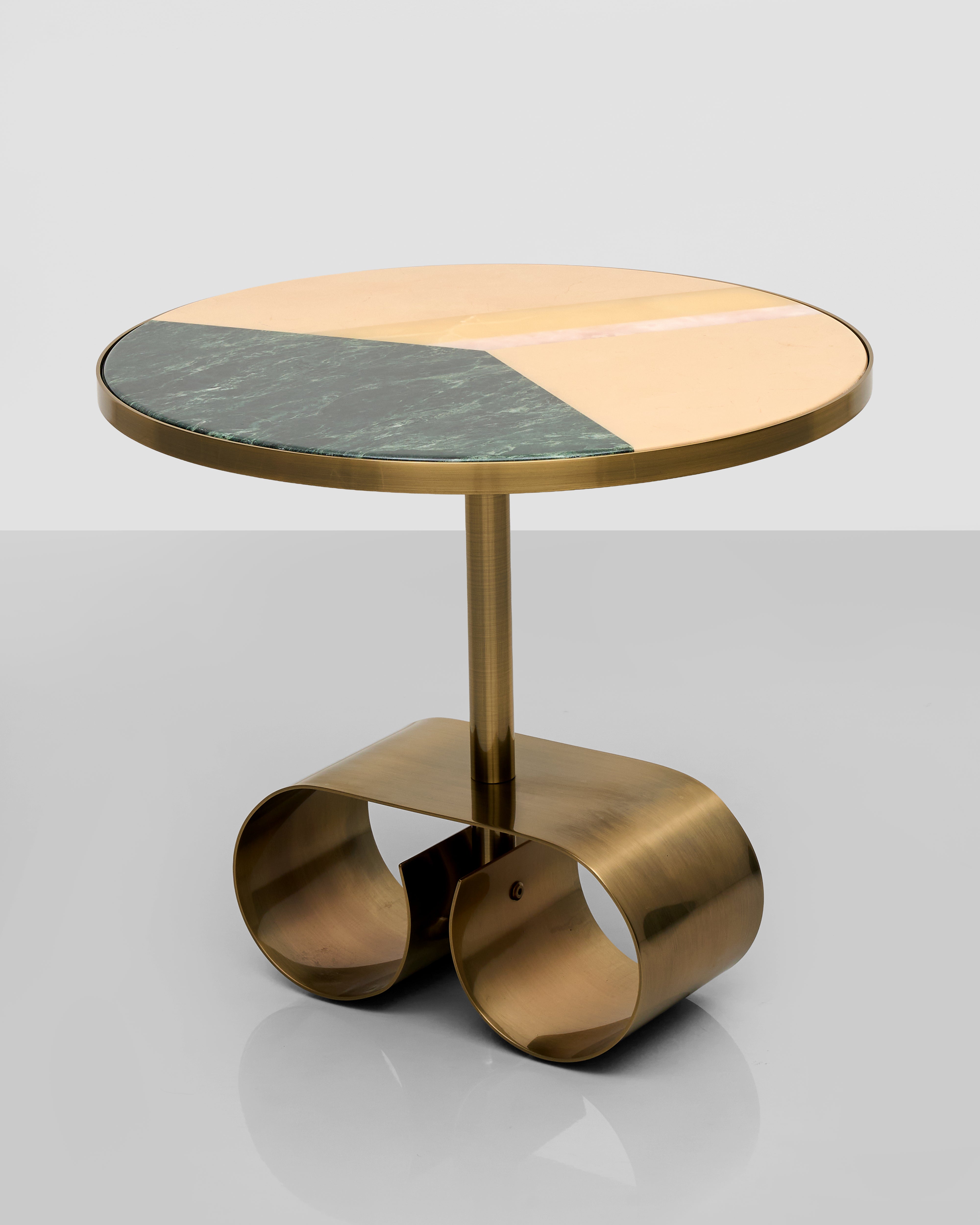 Small round table with brass base and marble top on a light gray background