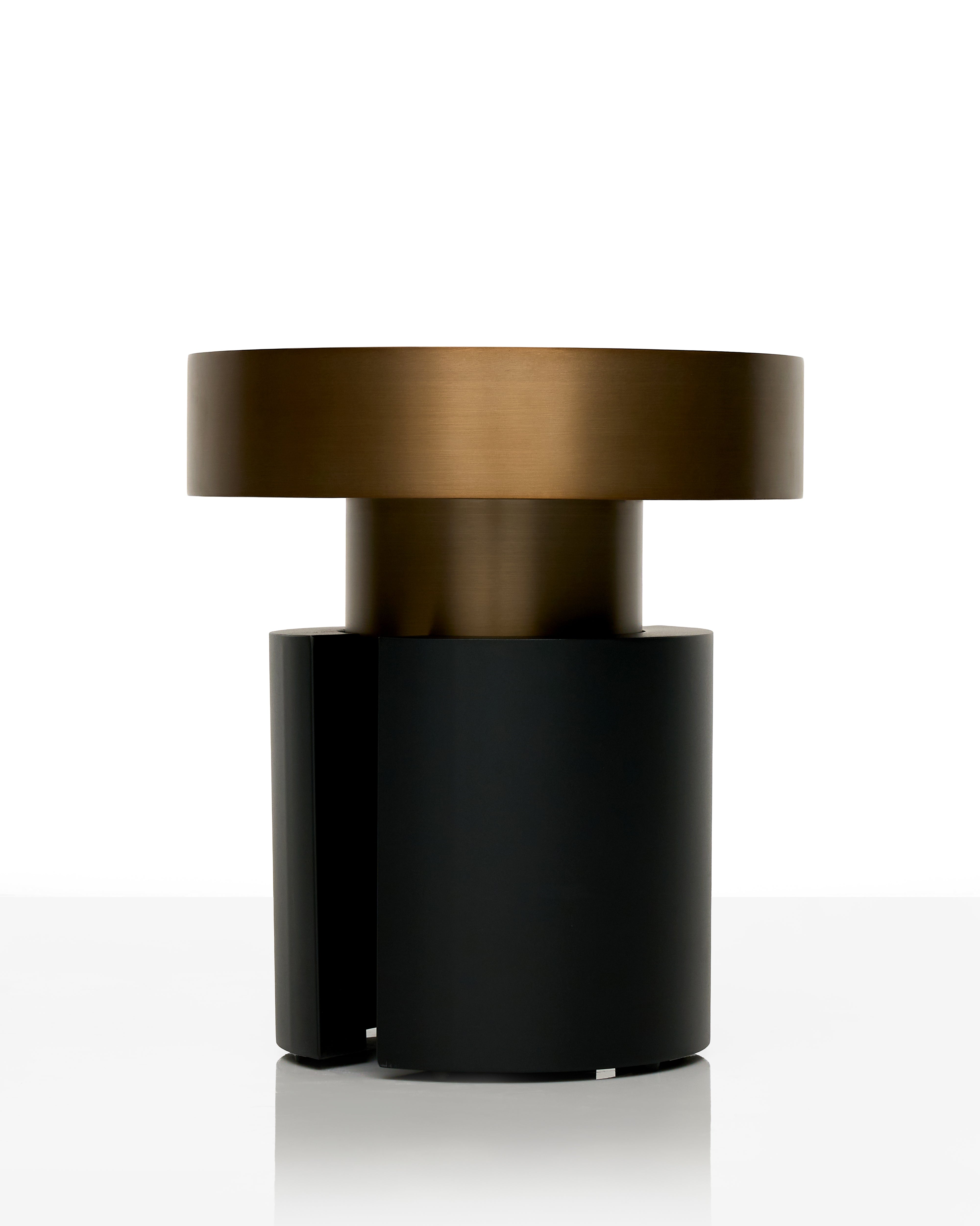 Two-toned cylindrical object with bronze top and black bottom on a white background