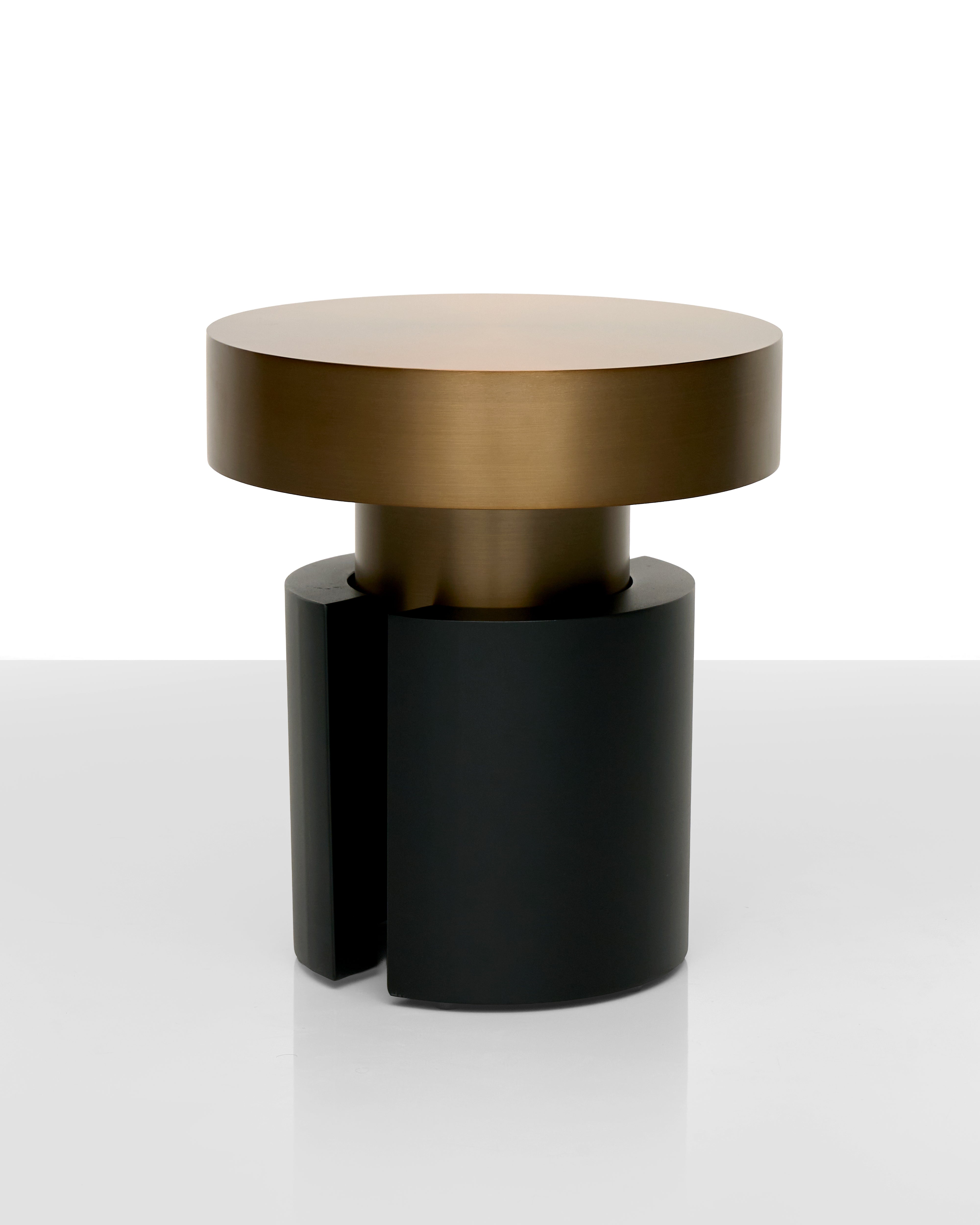 Modern side table with gold top and black base on a white background
