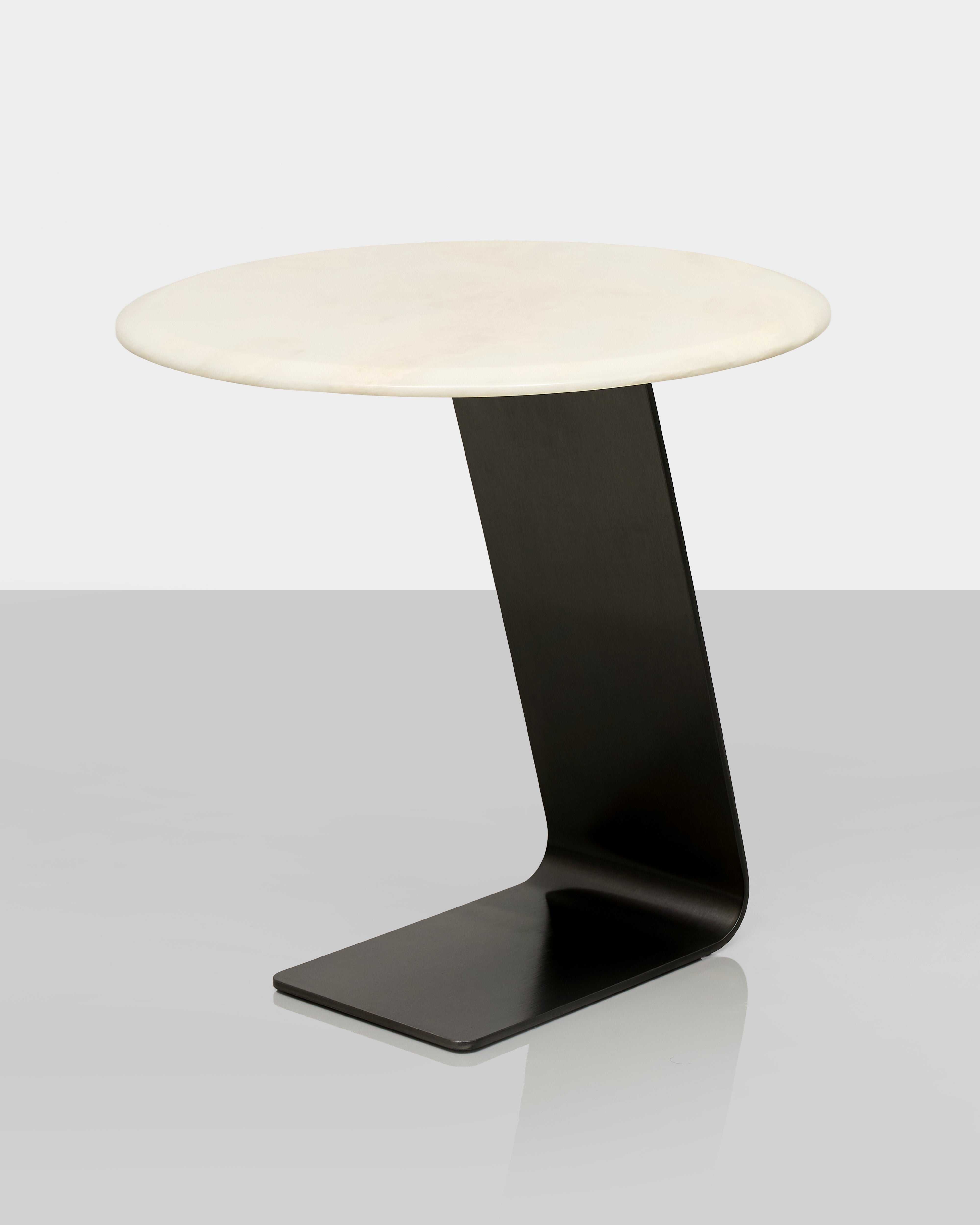 Modern side table with a white round top and black curved base on a light gray background