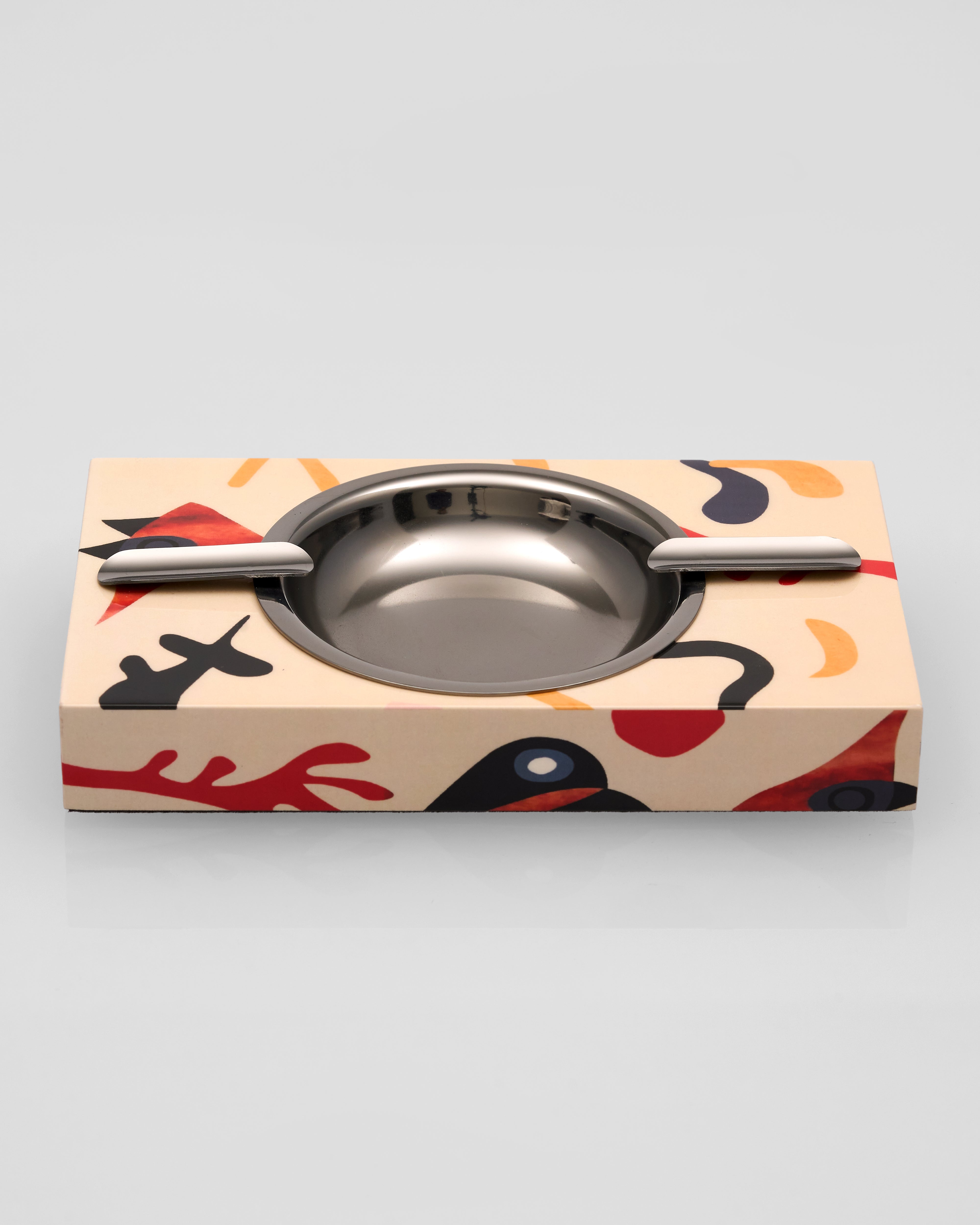 Metallic ashtray with abstract design on a light gray background