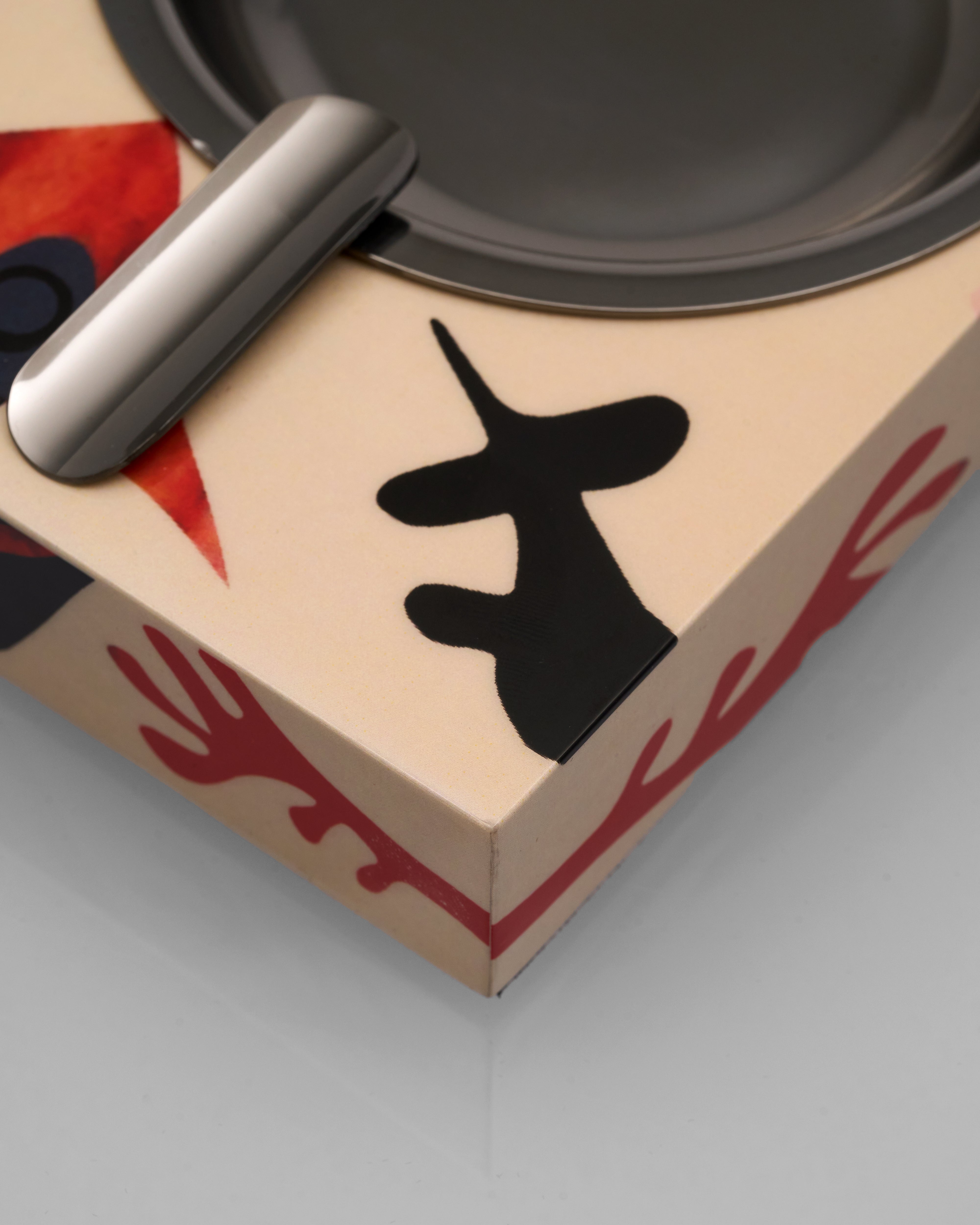 Close-up of a product with a black design on a beige box with red patterns.