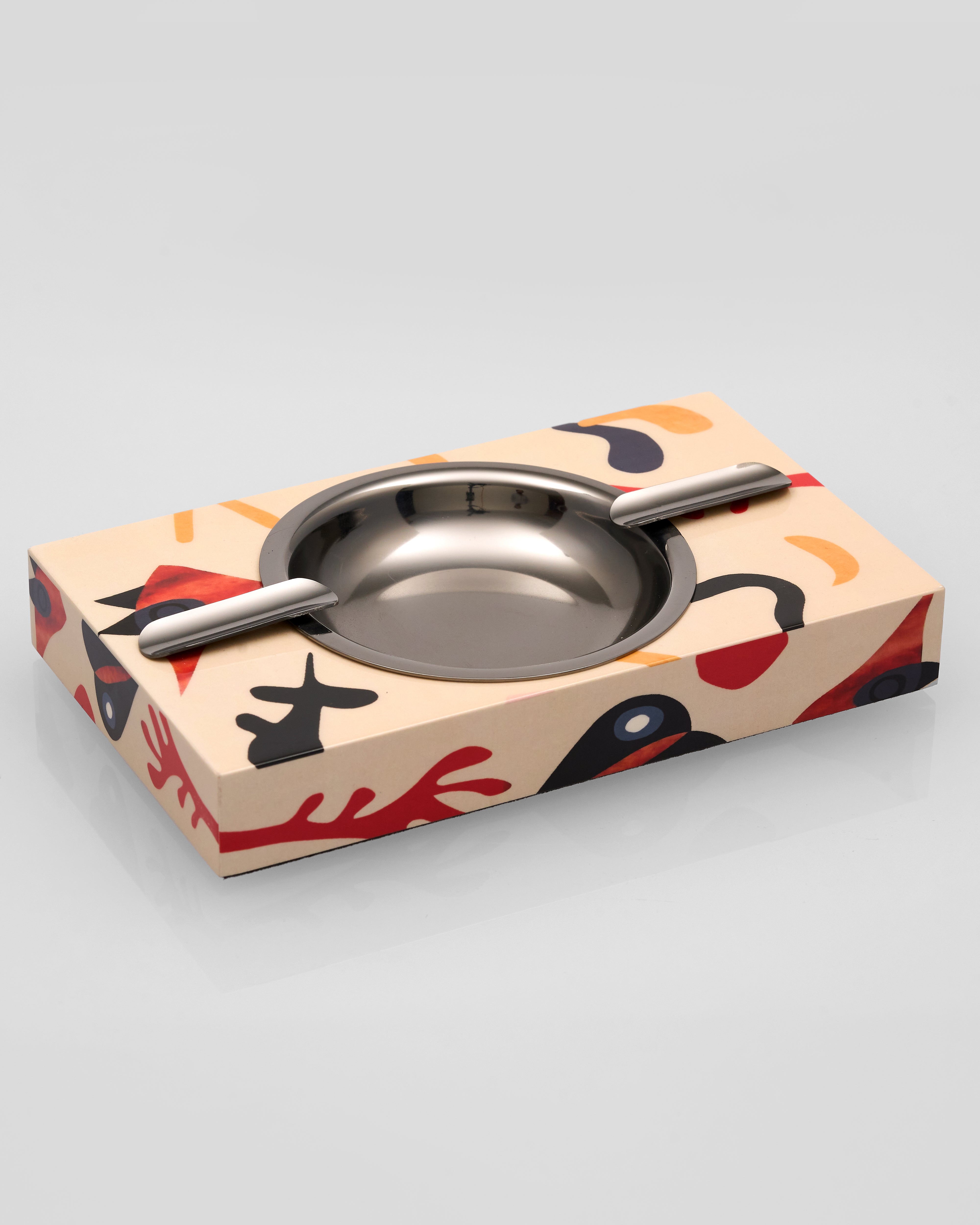 Stainless steel ashtray on a decorative box with abstract patterns
