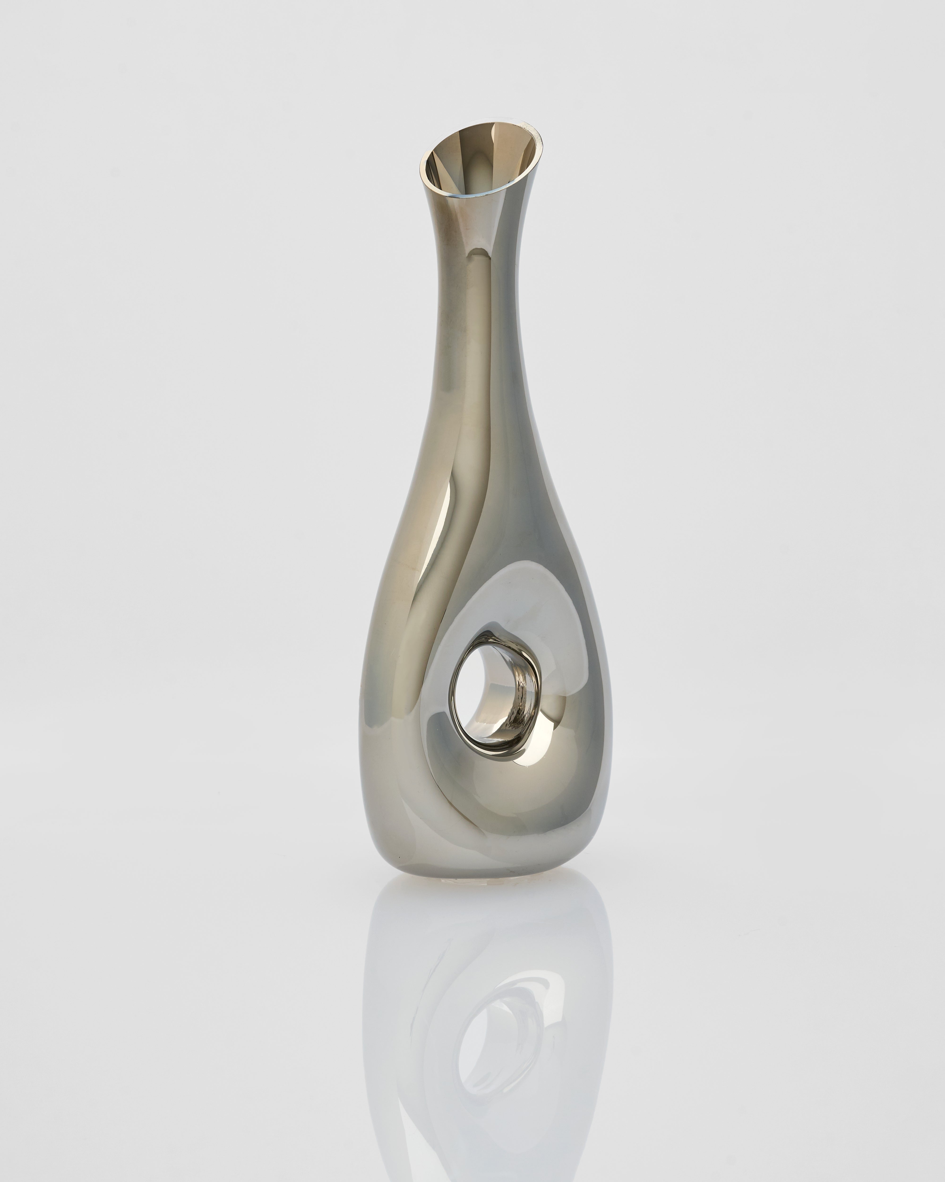 Silver vase on a reflective surface with a light gray background