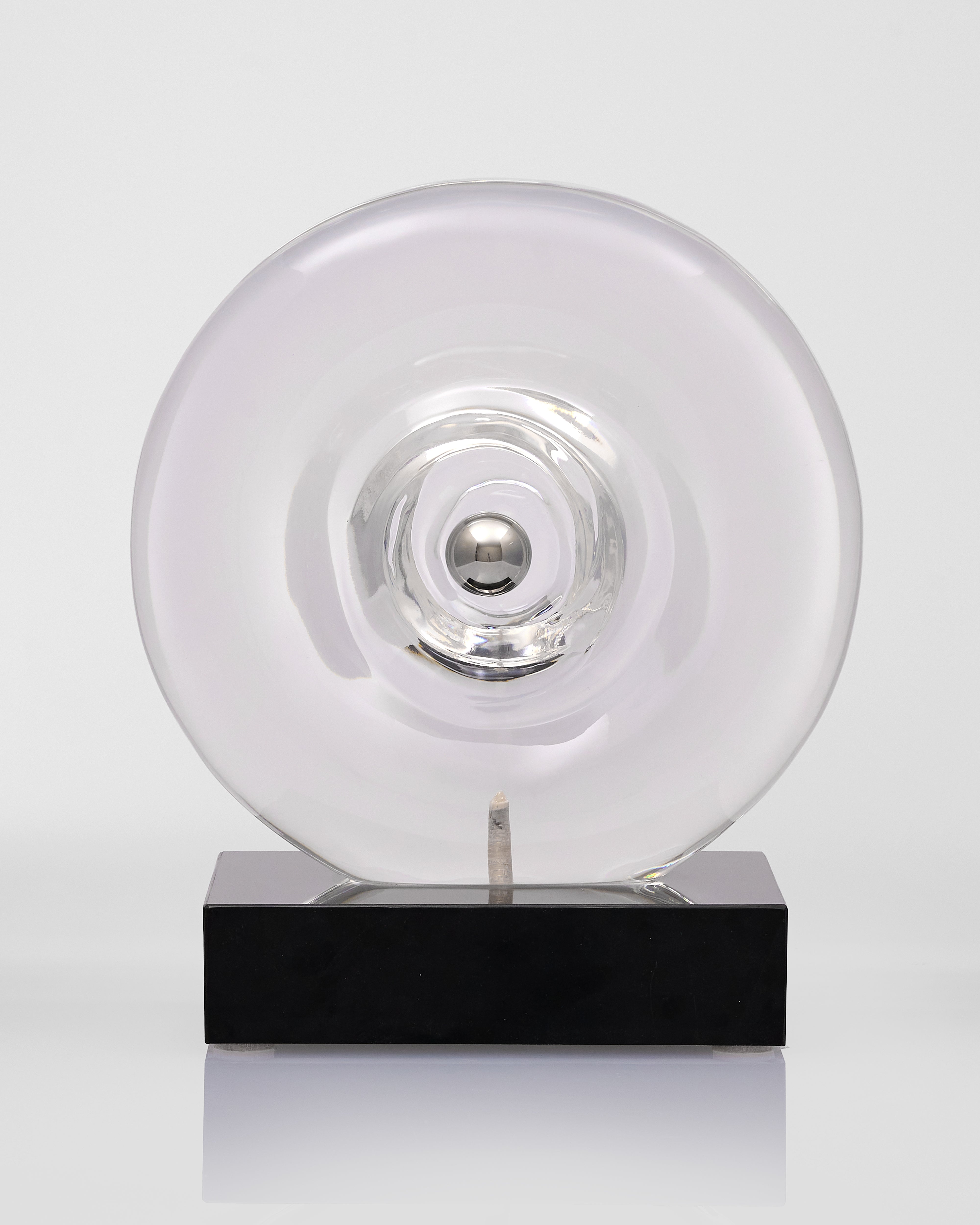 Clear acrylic transparent disc on a black base against a white background