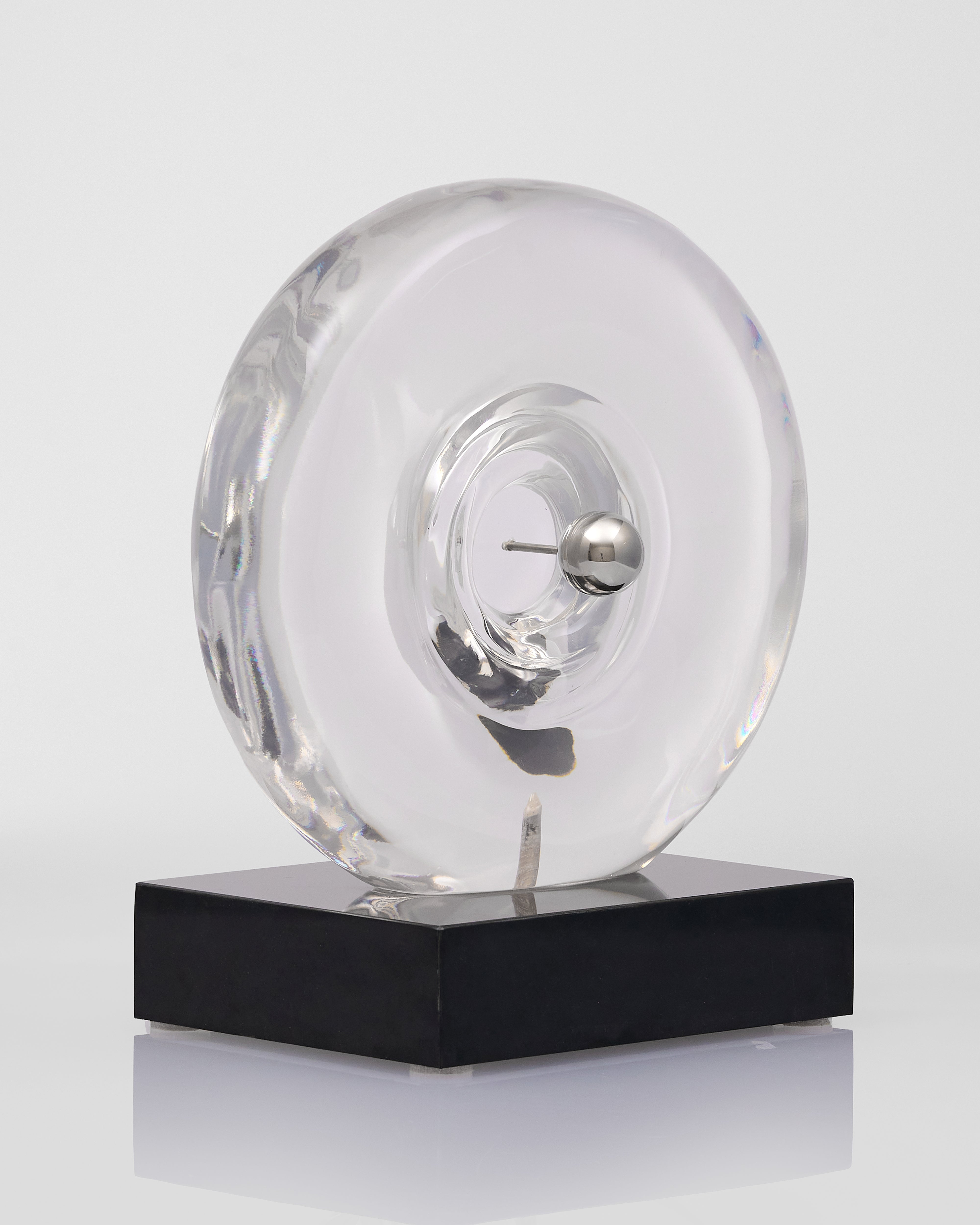 Clear acrylic transparent object on a black base against a white background