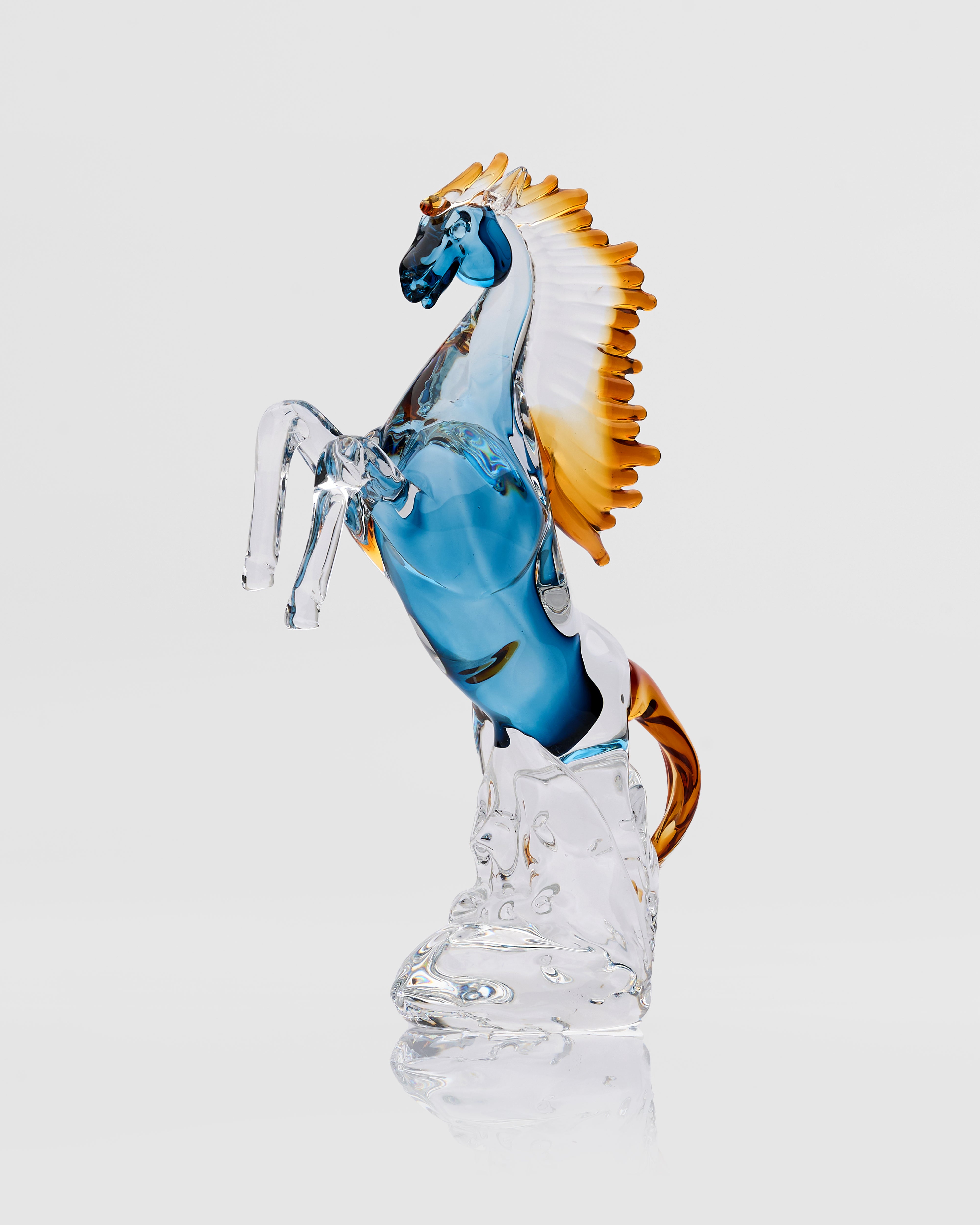 Glass horse figurine with blue body and orange mane on a white background