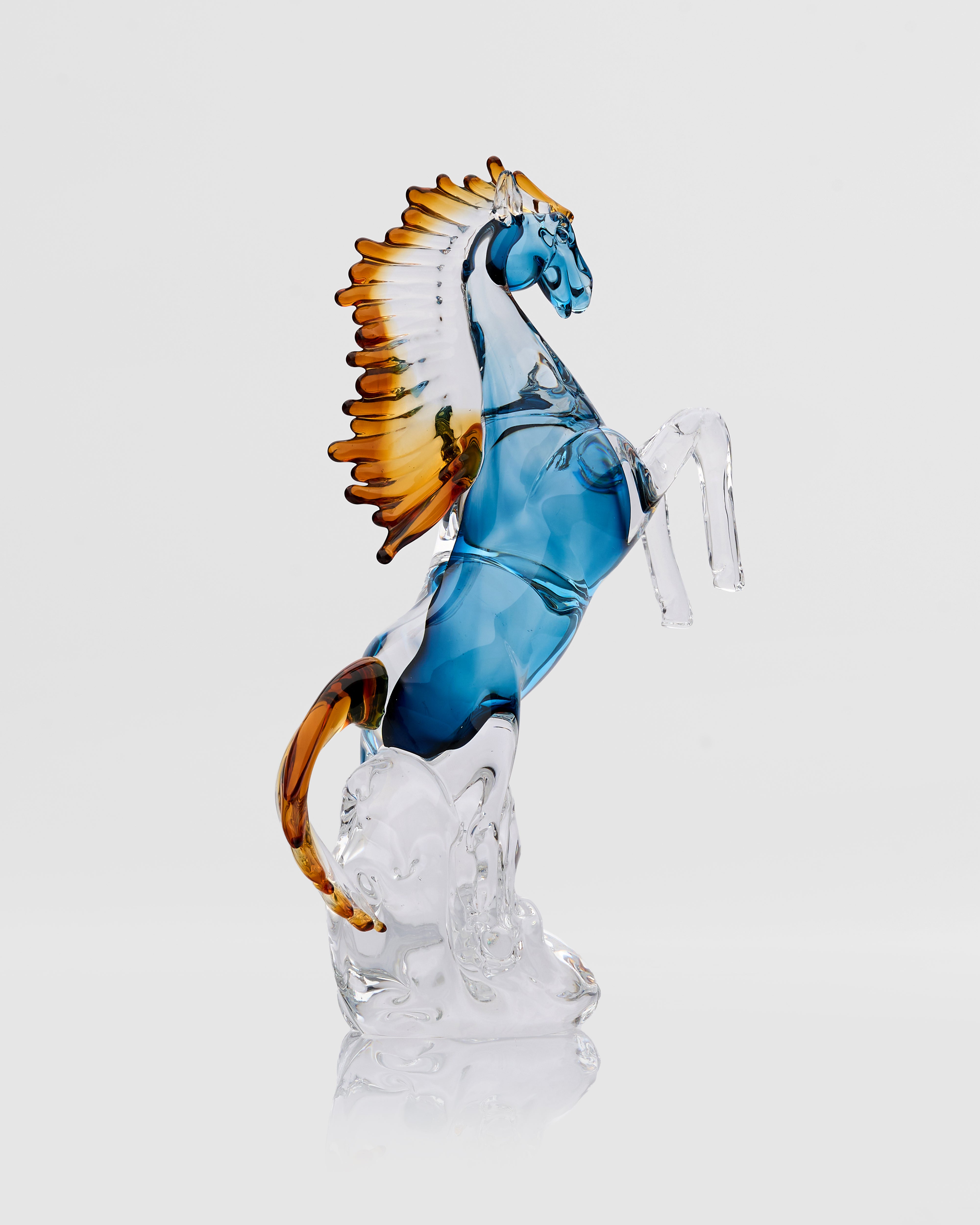 Glass horse figurine with blue body and brown mane on a white background
