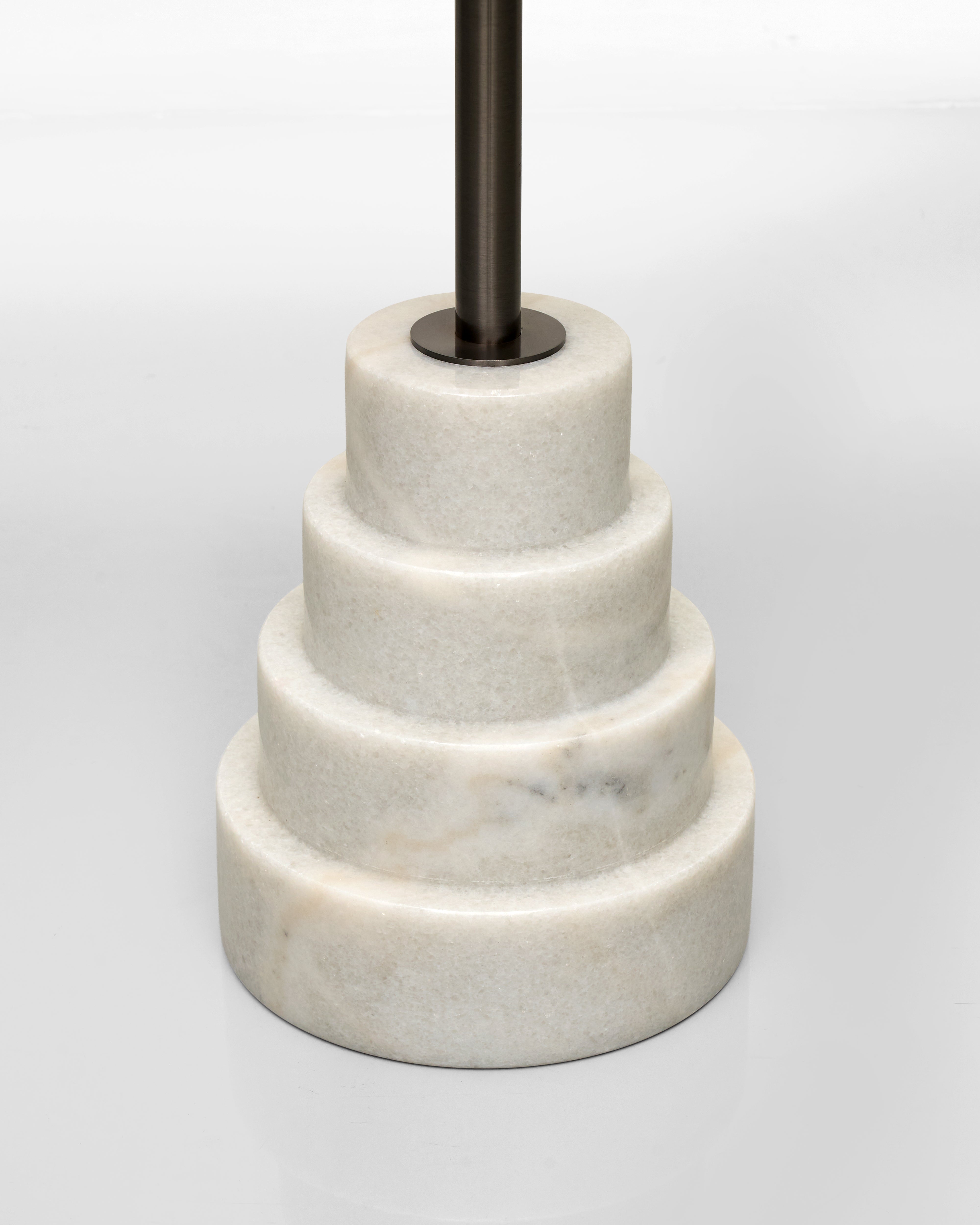 Marble tiered stand with black metal rod on a light gray background