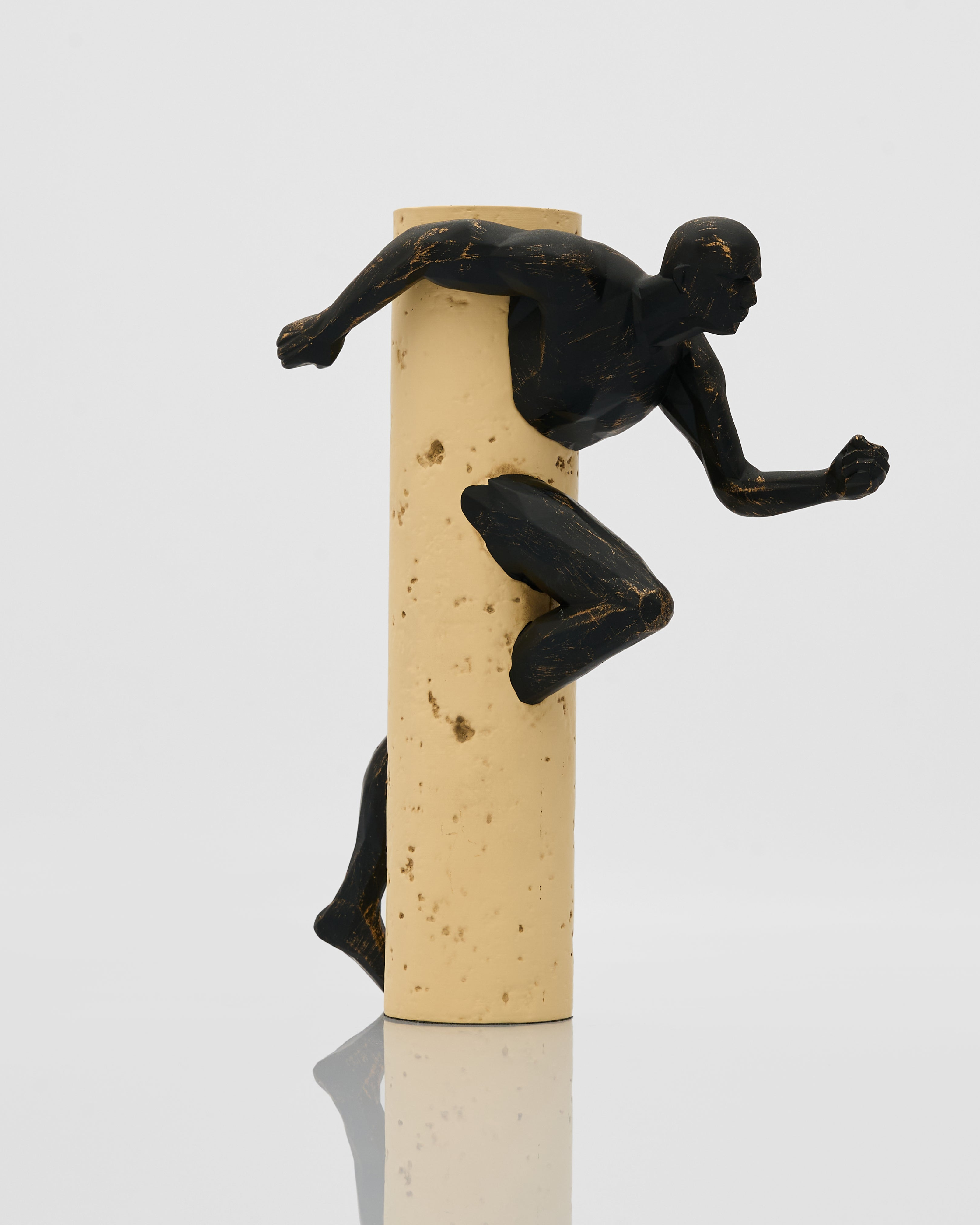 Black figurine of a runner on top of a cork stopper against a white background