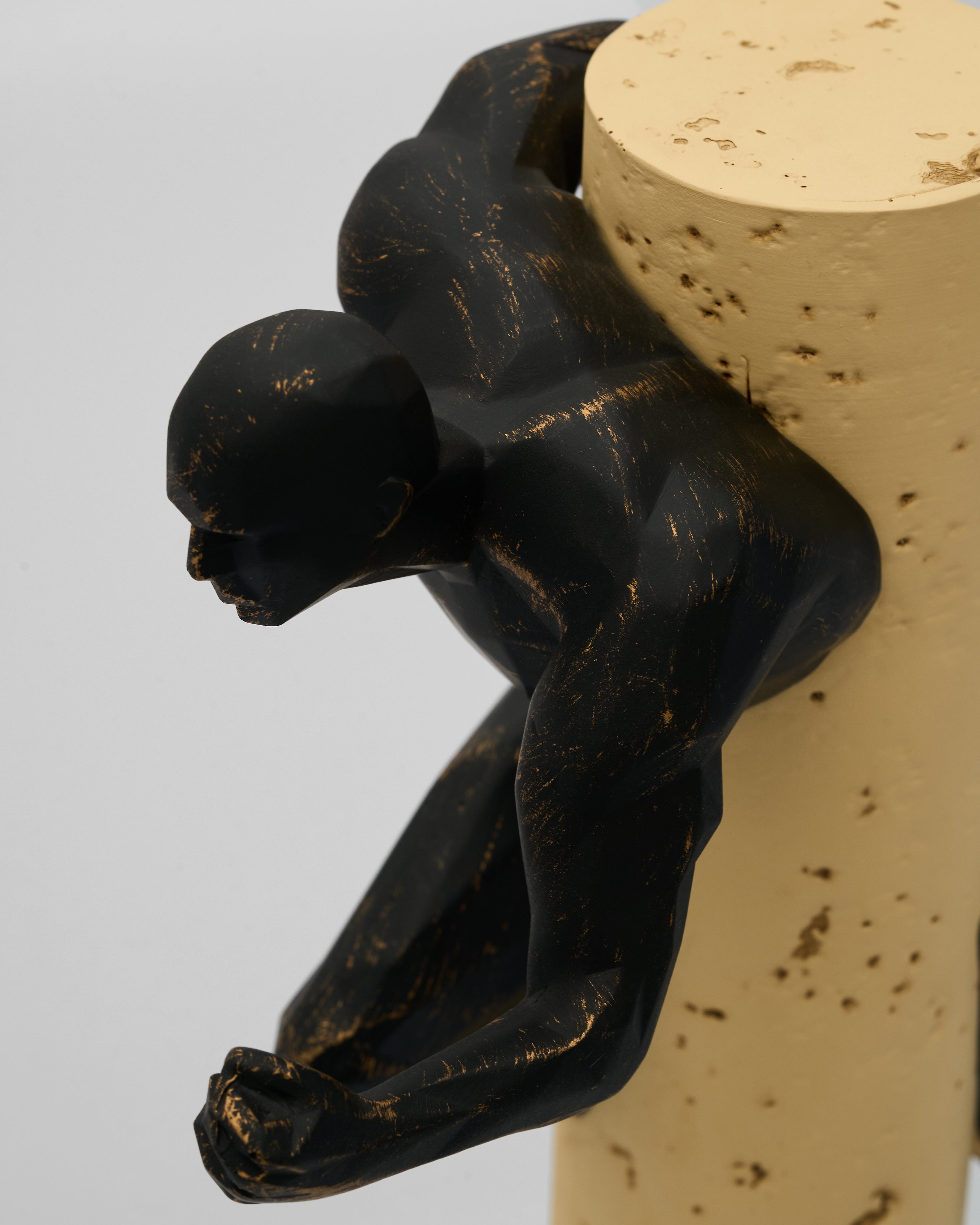 Black figurine of a person holding a cylindrical object on a white background