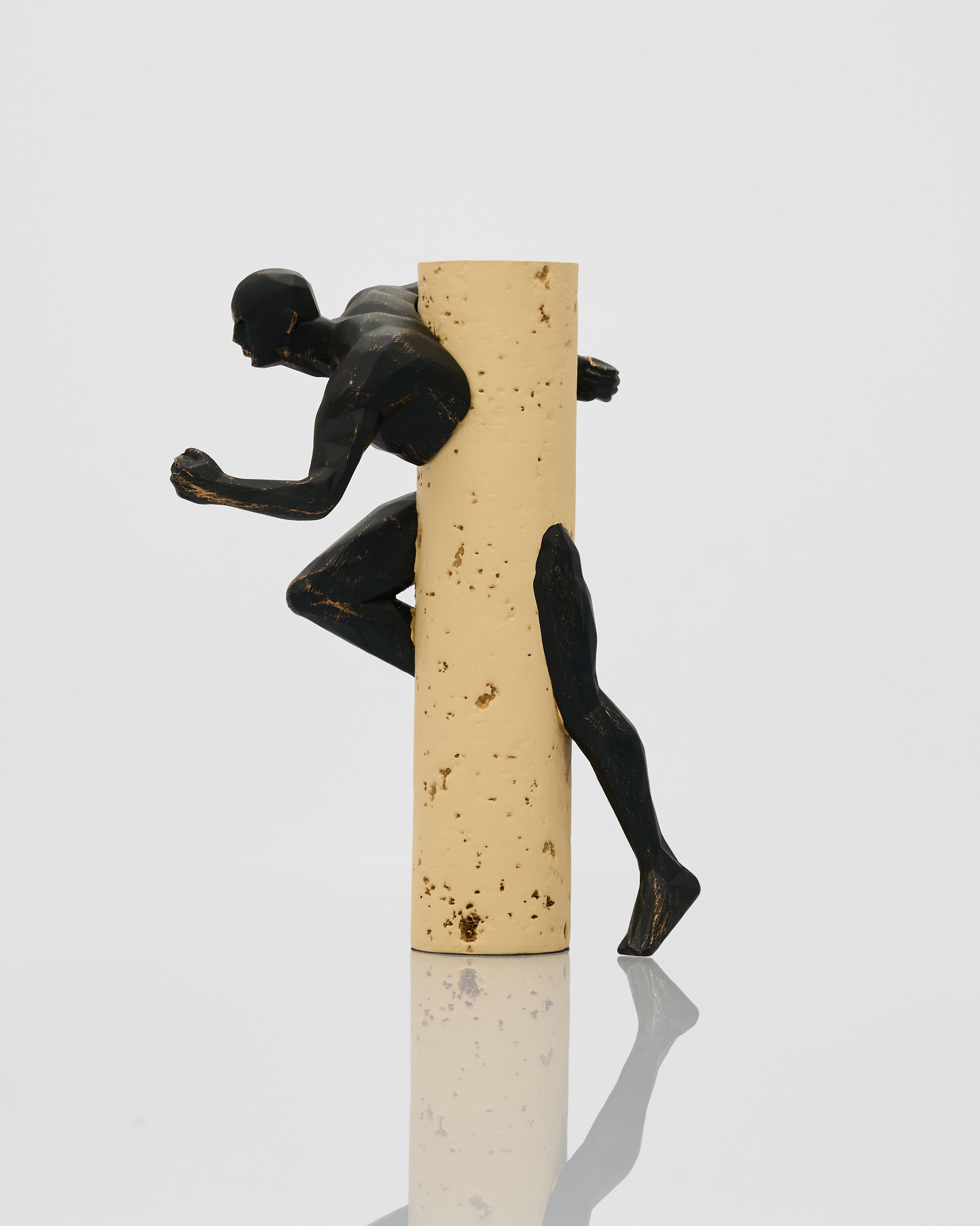 Black figurine of a runner climbing a cork stopper on a white background
