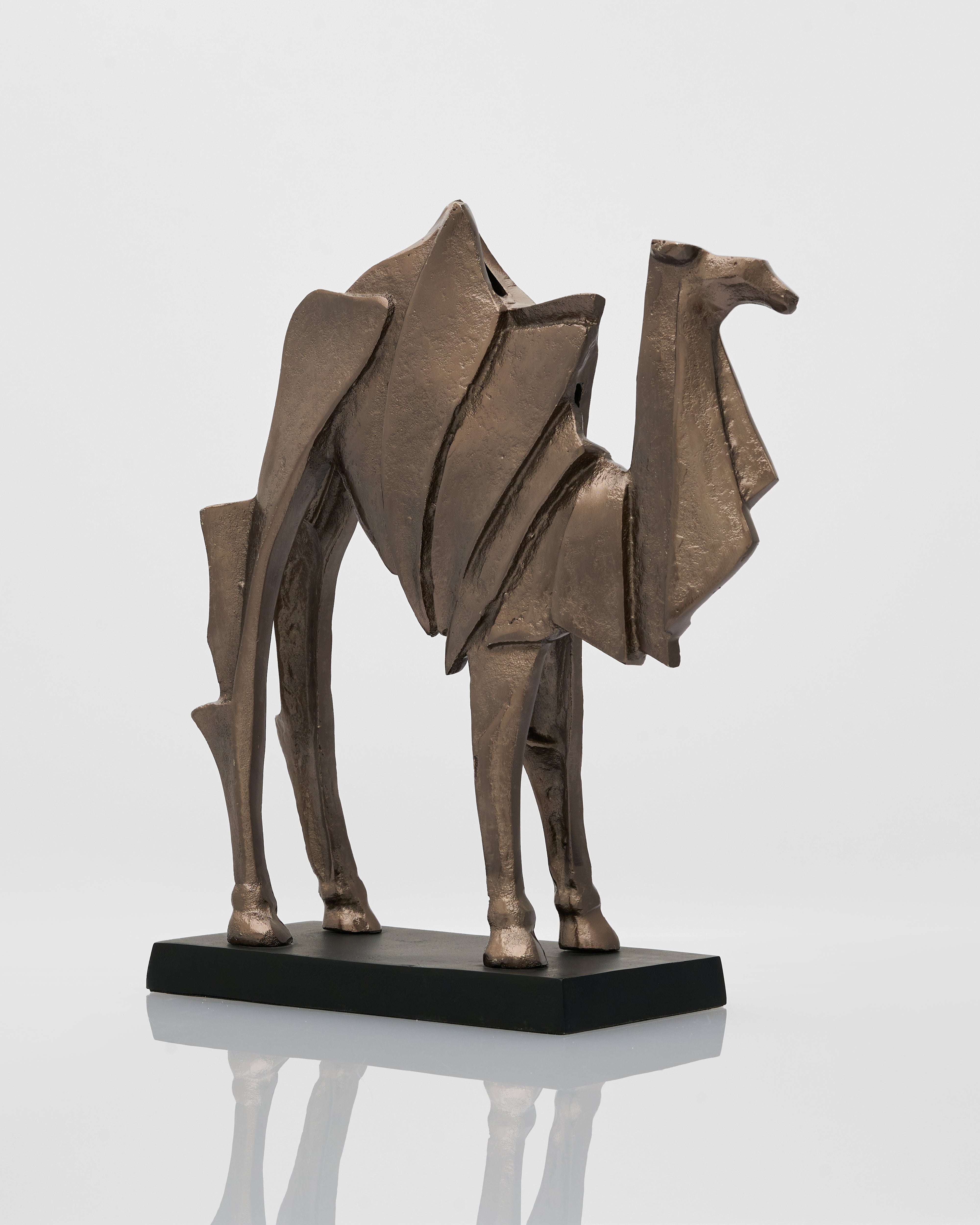 Bronze sculpture of a camel on a reflective surface with a white background