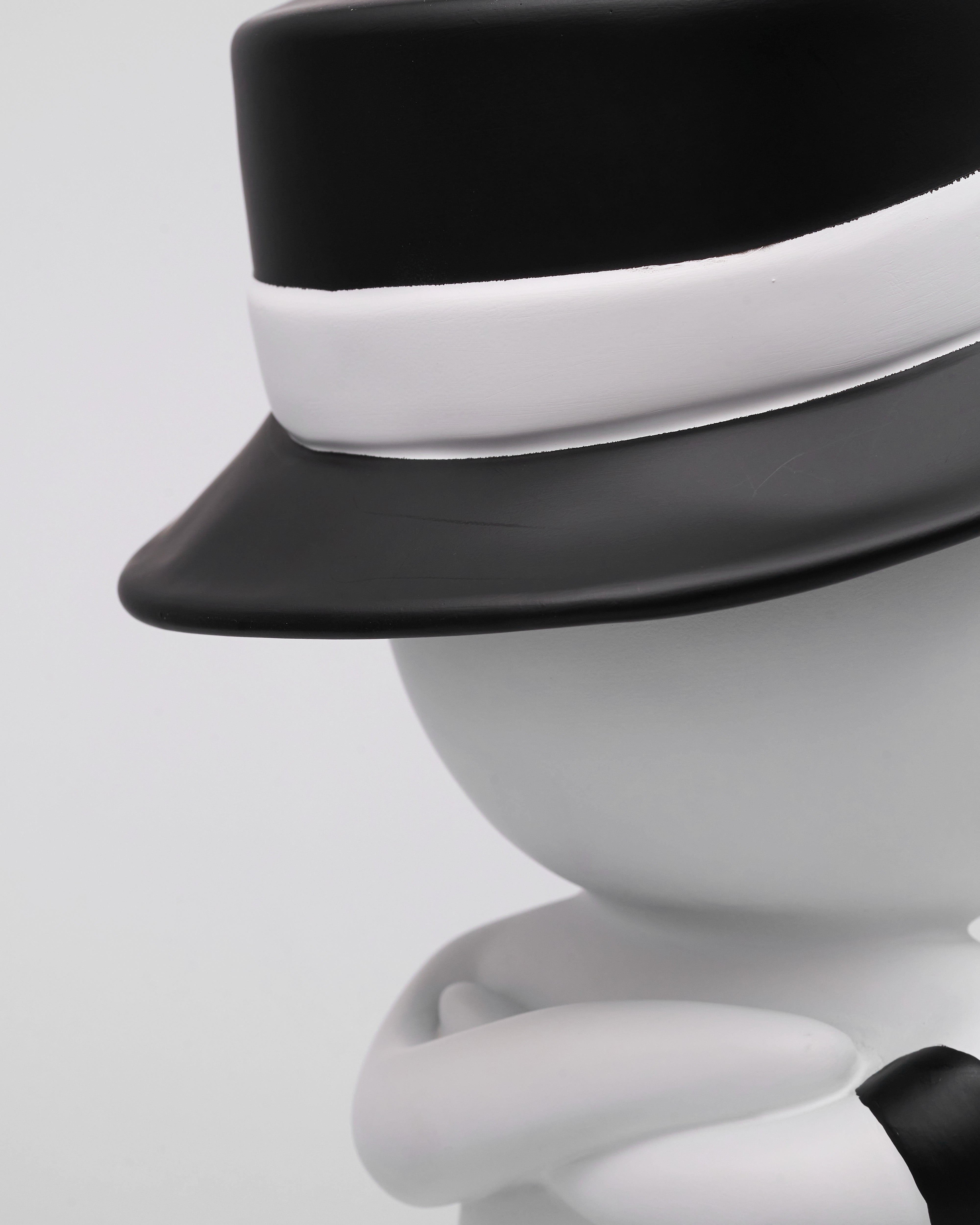 White character wearing a black hat with a white band on a light gray background
