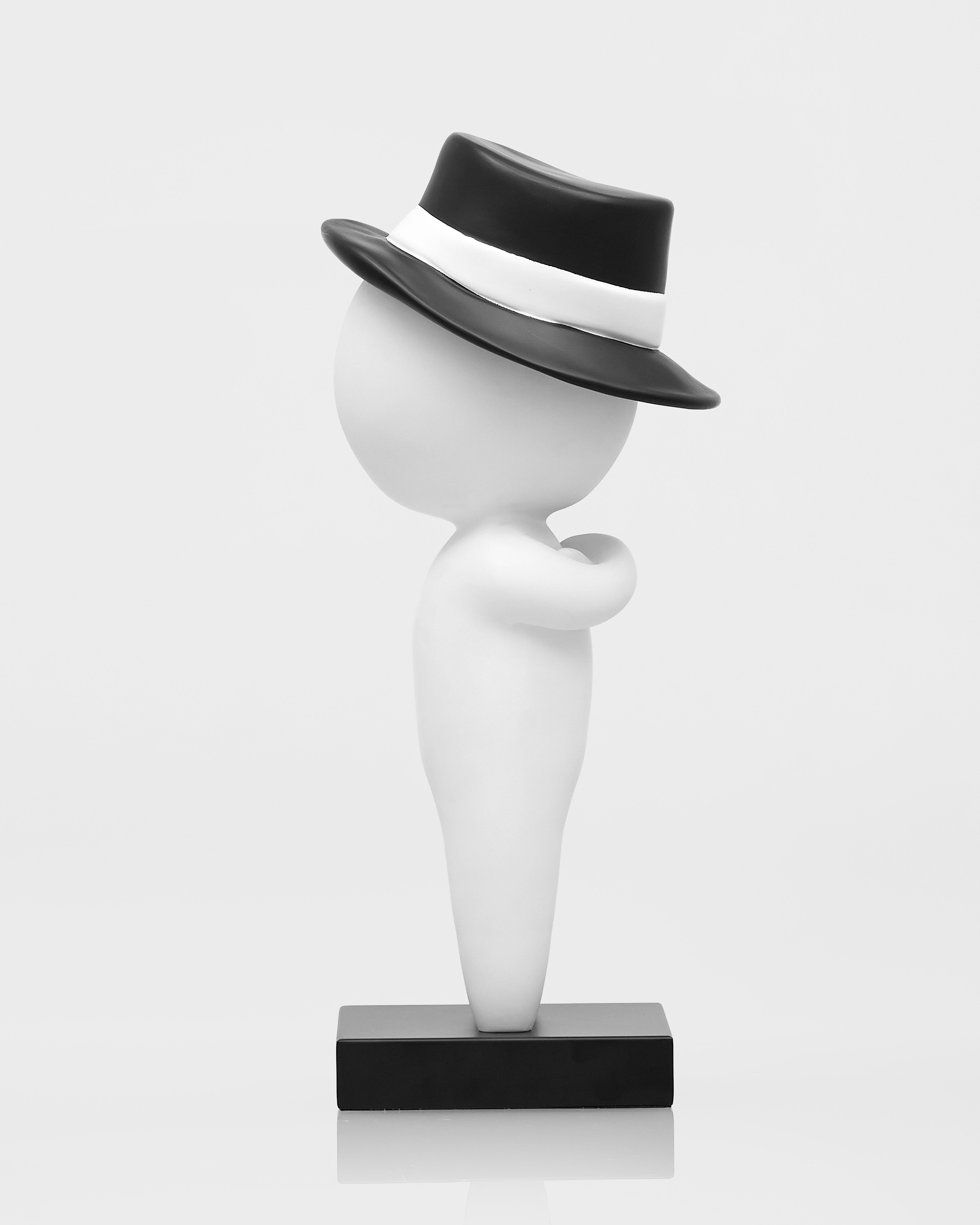 White sculpture with a black hat on a white background