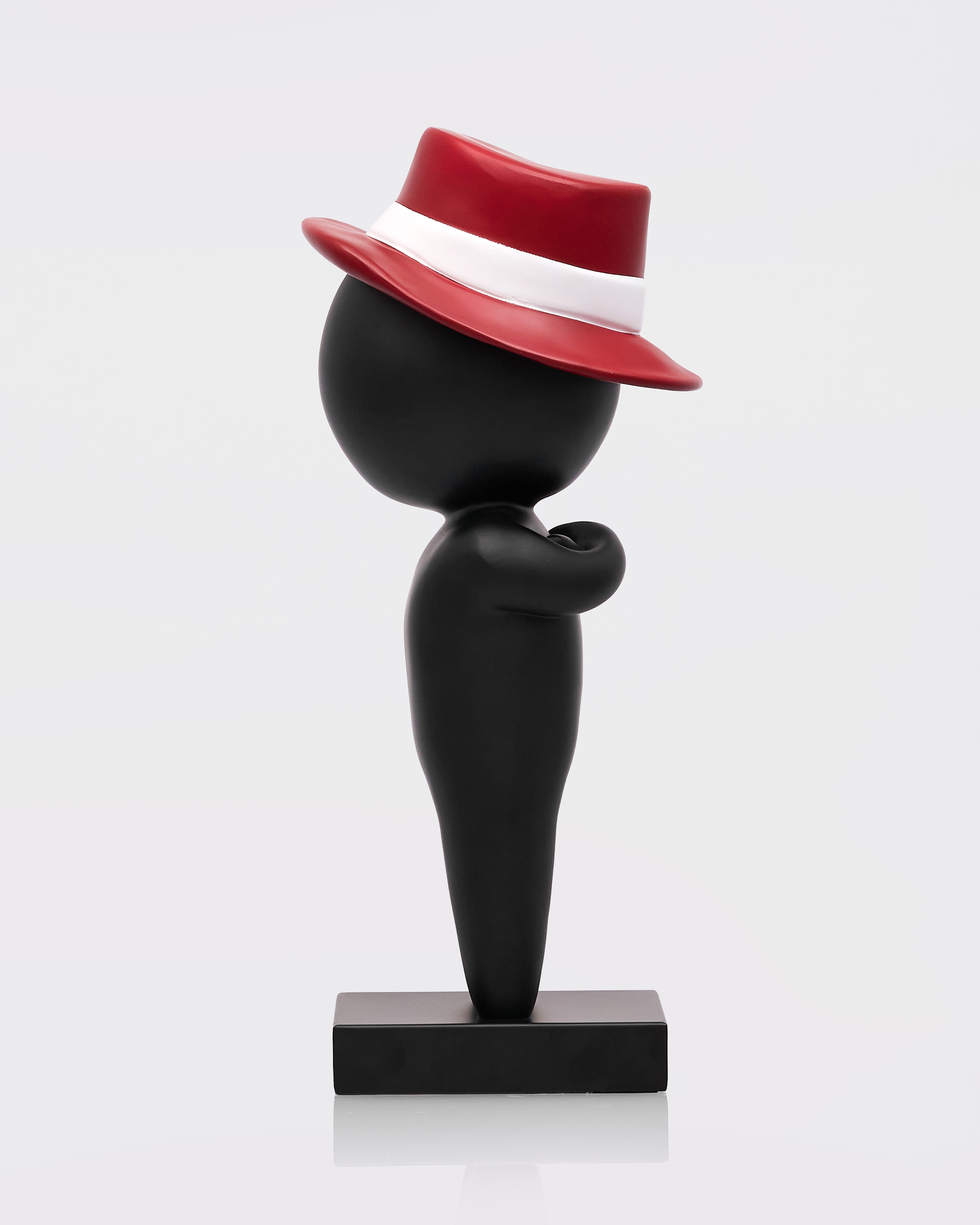 Black sculpture with a red hat on a white background
