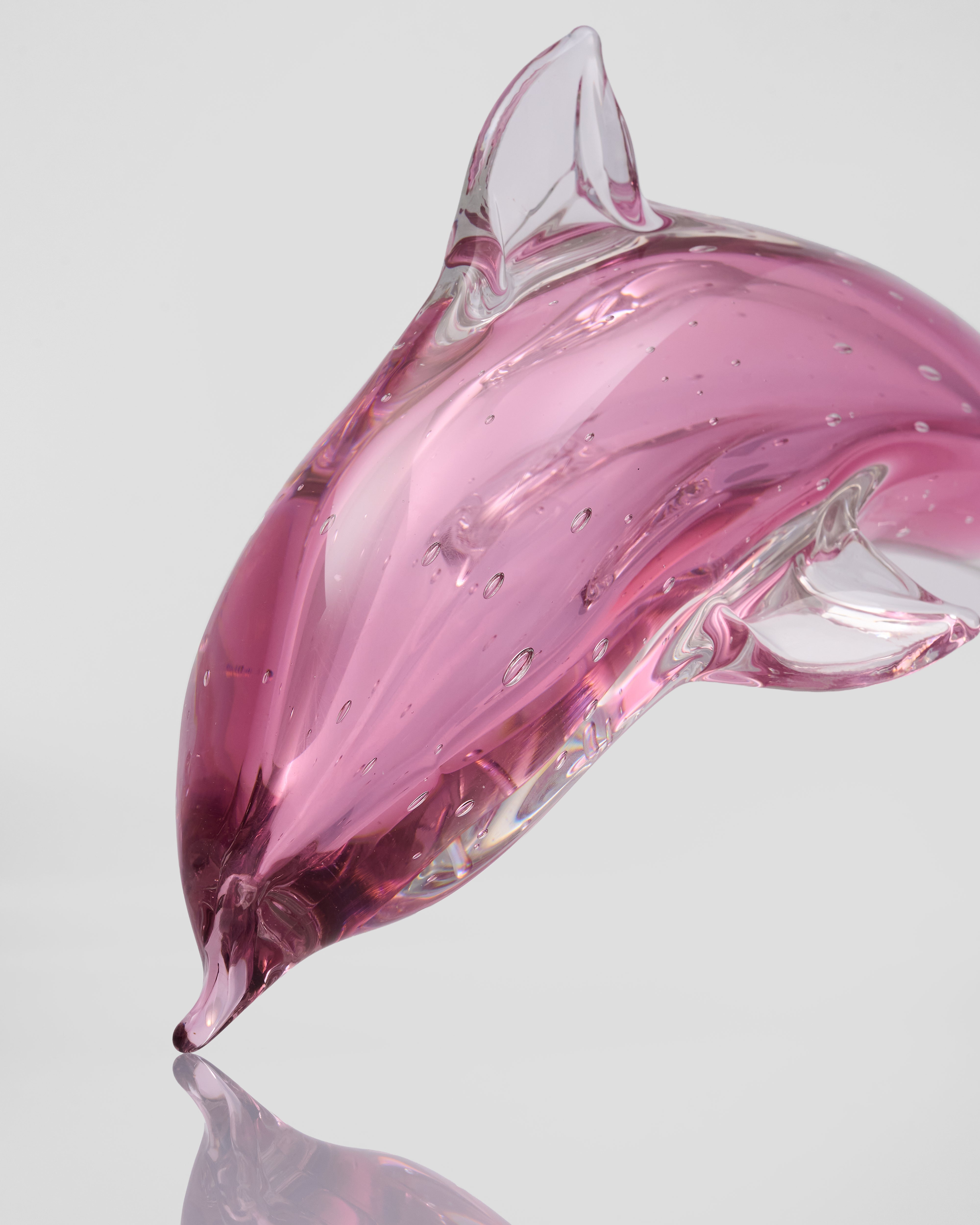 Pink glass dolphin sculpture on a light gray background