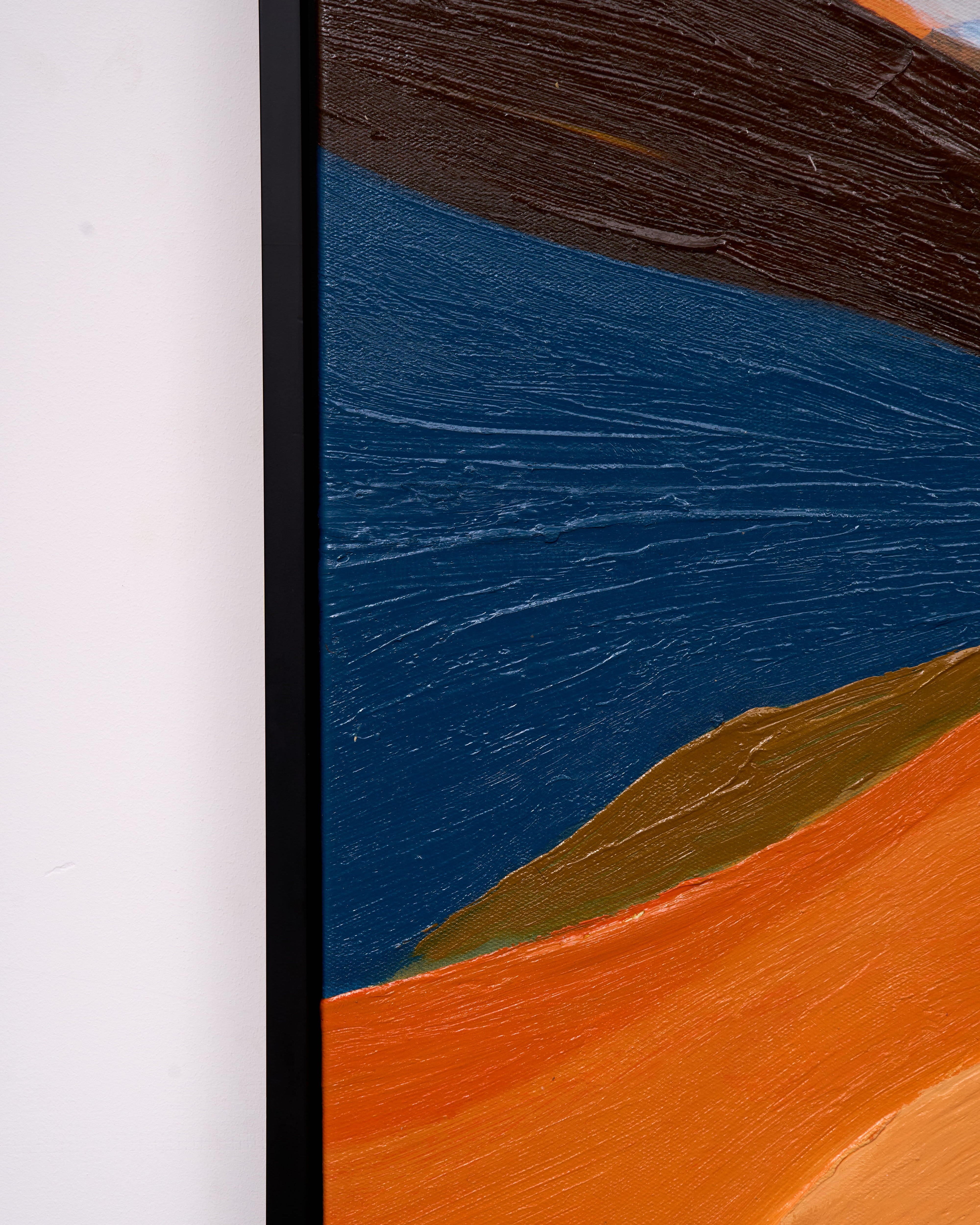 Close-up of a framed abstract landscape painting showing textured brushstrokes of deep blue, orange, brown, and tan against a white wall.
