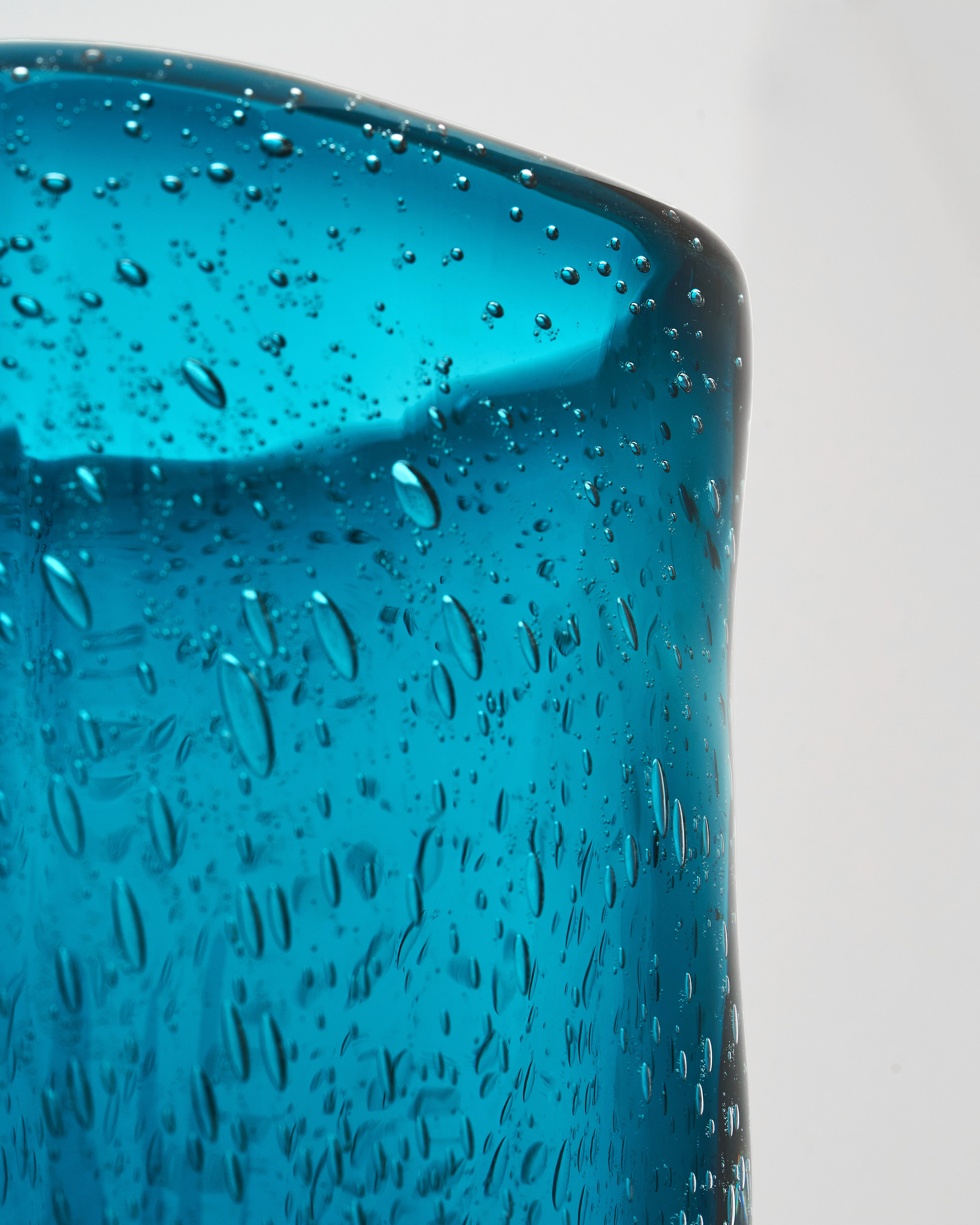 Close-up of a blue glass with water droplets on a white background