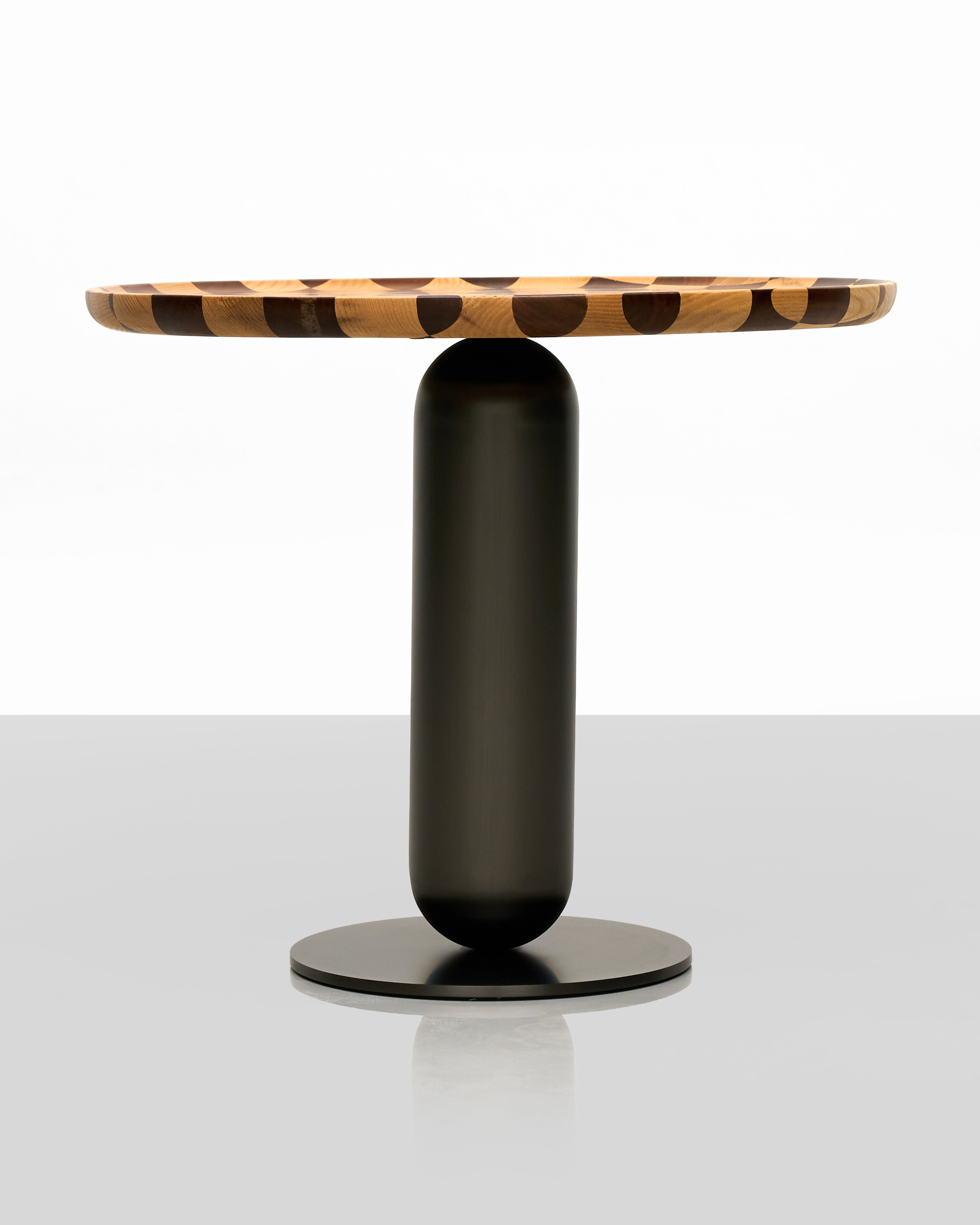 Modern side table with a black cylindrical base and tortoiseshell-patterned top on a white background