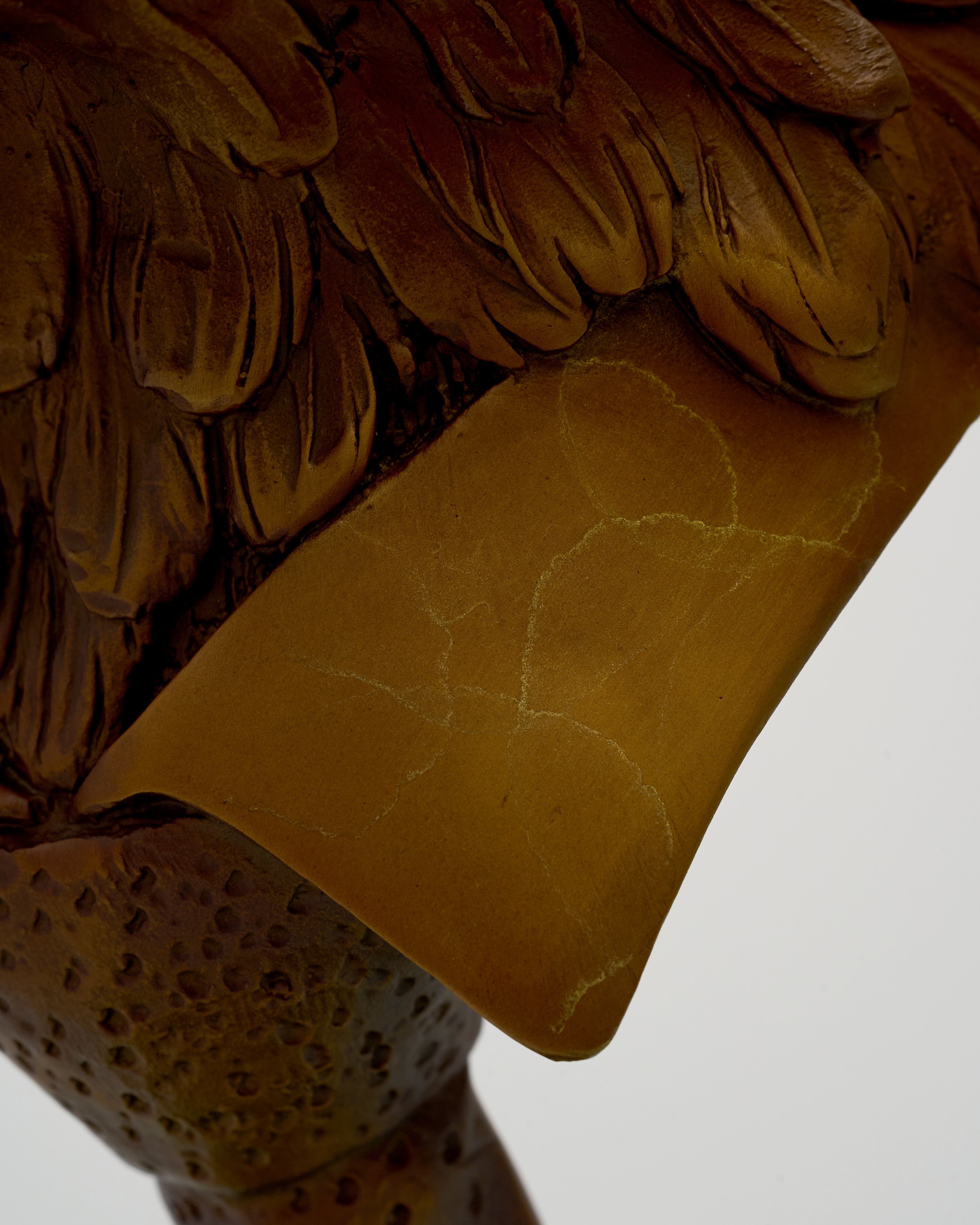 Close-up of a brown wooden eagles head with a heart design on a white background