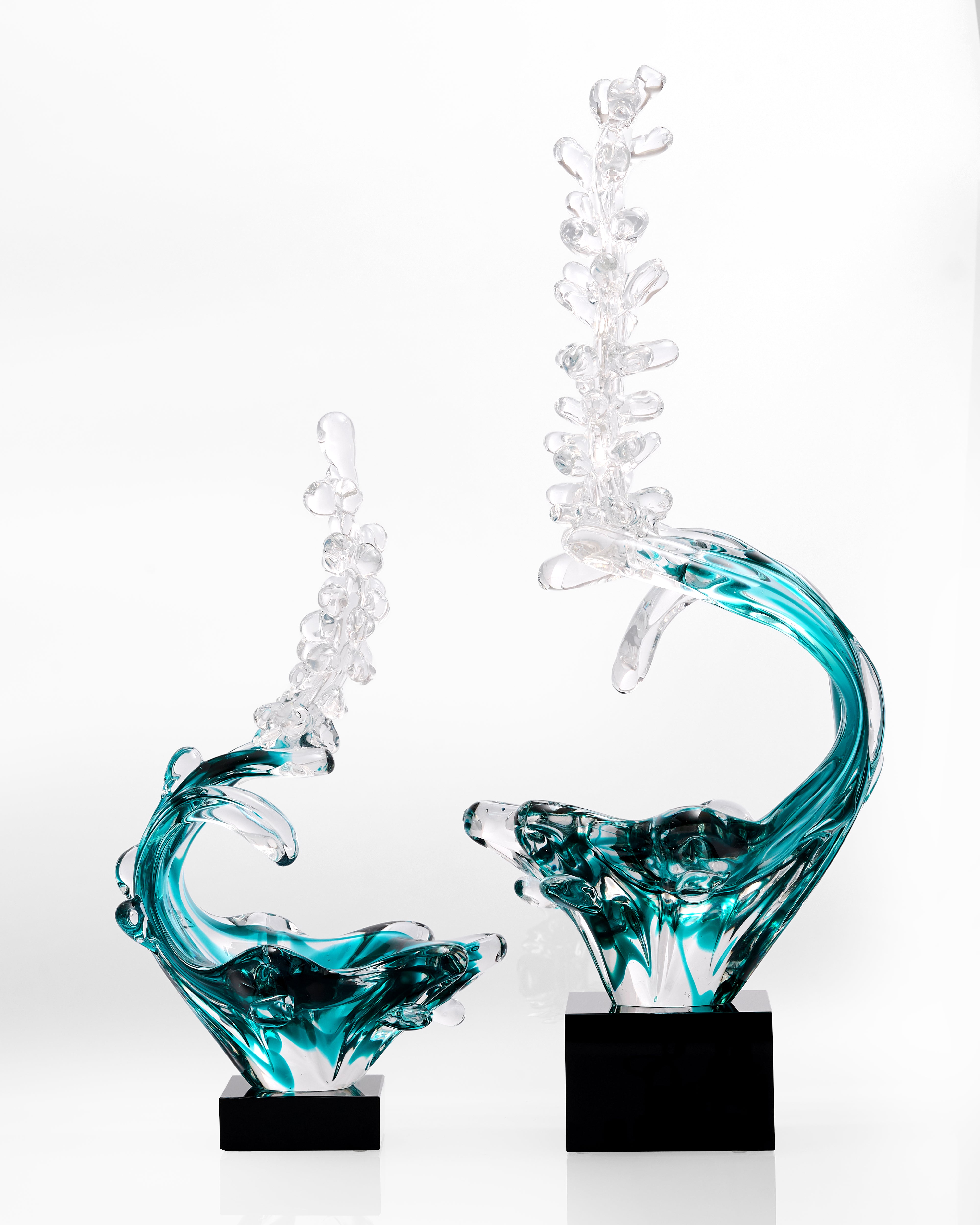 Two glass sculptures with wavy designs on a white background