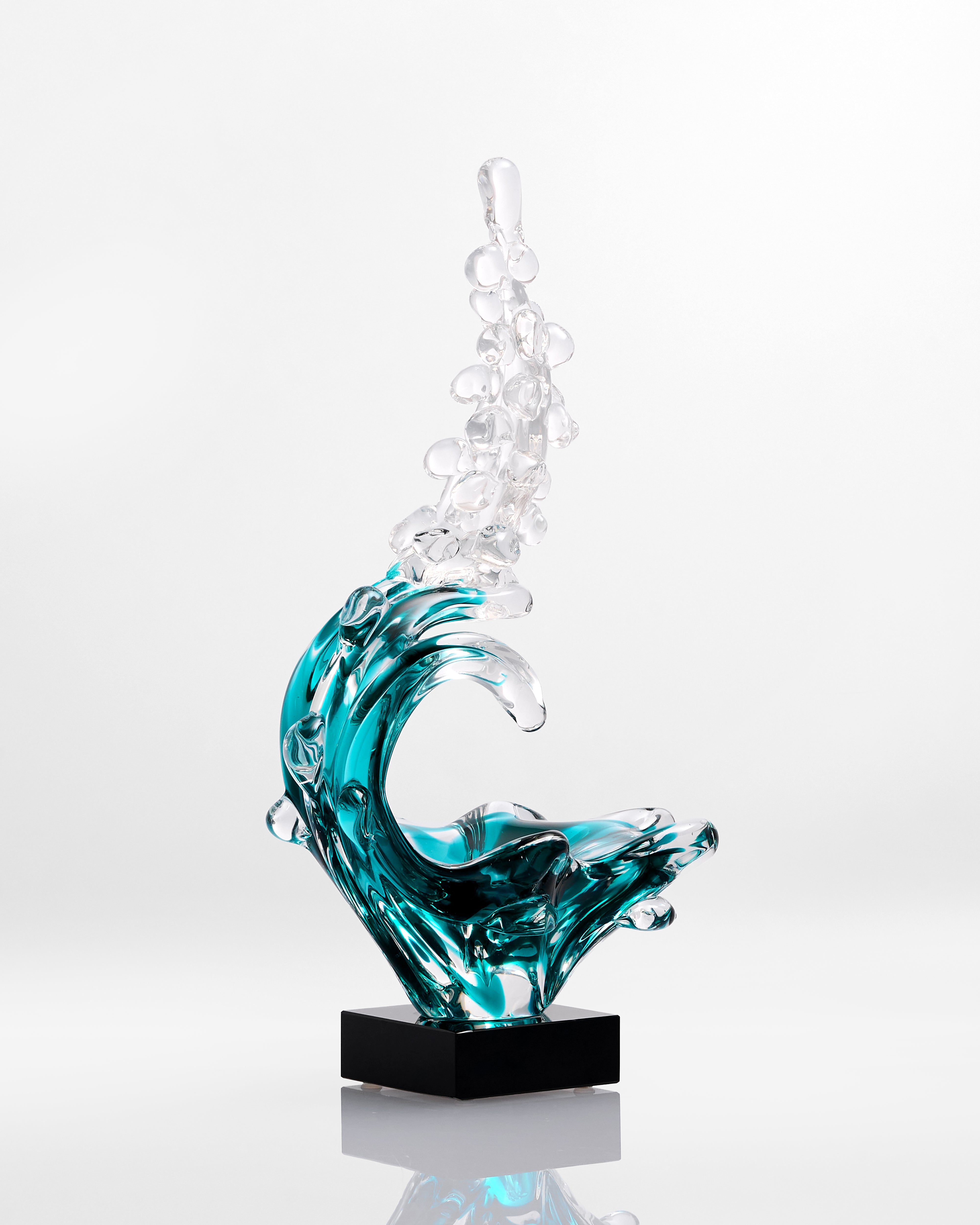 Glass sculpture of a wave with bubbles on a white background