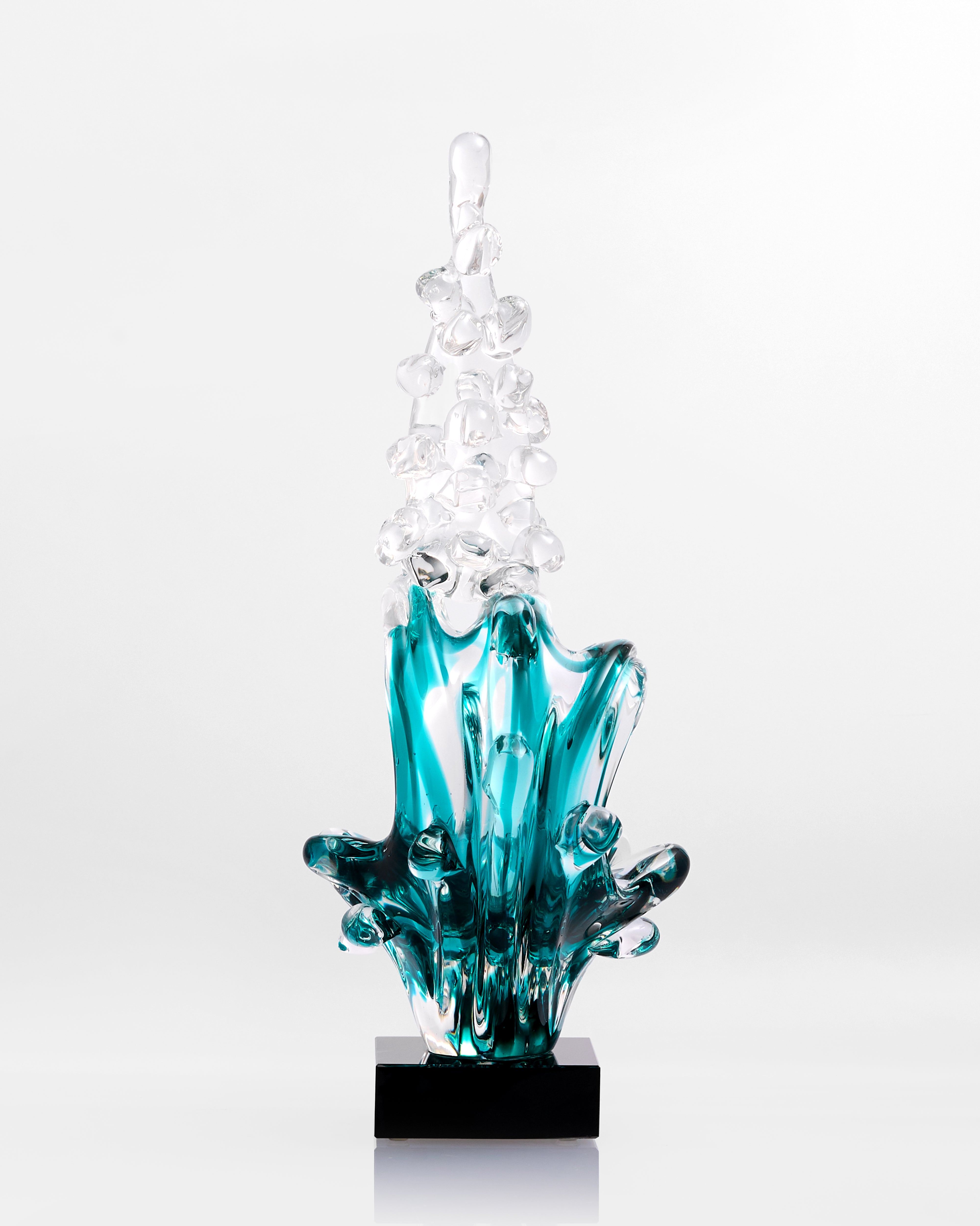 Glass sculpture with blue and clear elements on a white background