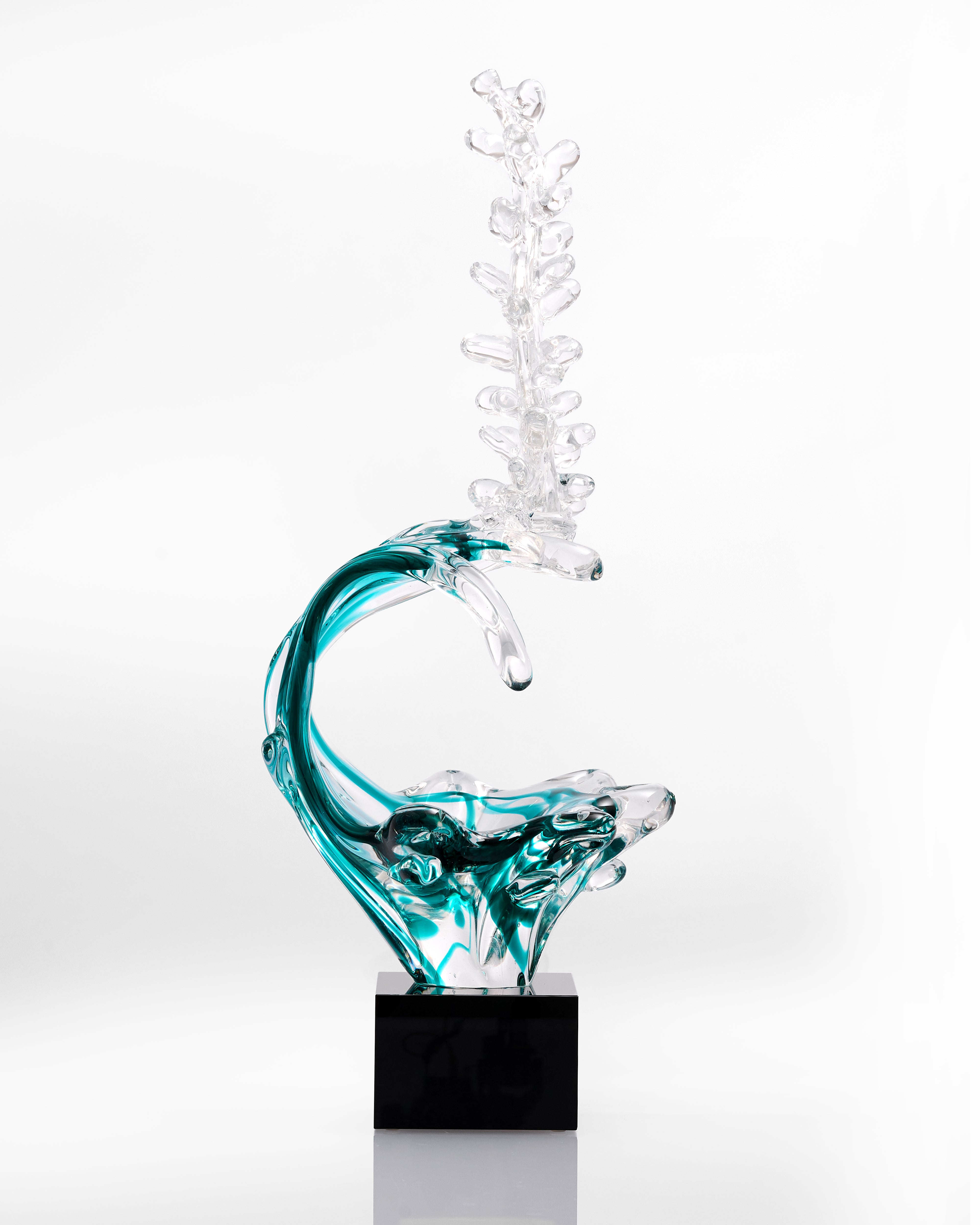Glass sculpture of a wave with a black base on a white background