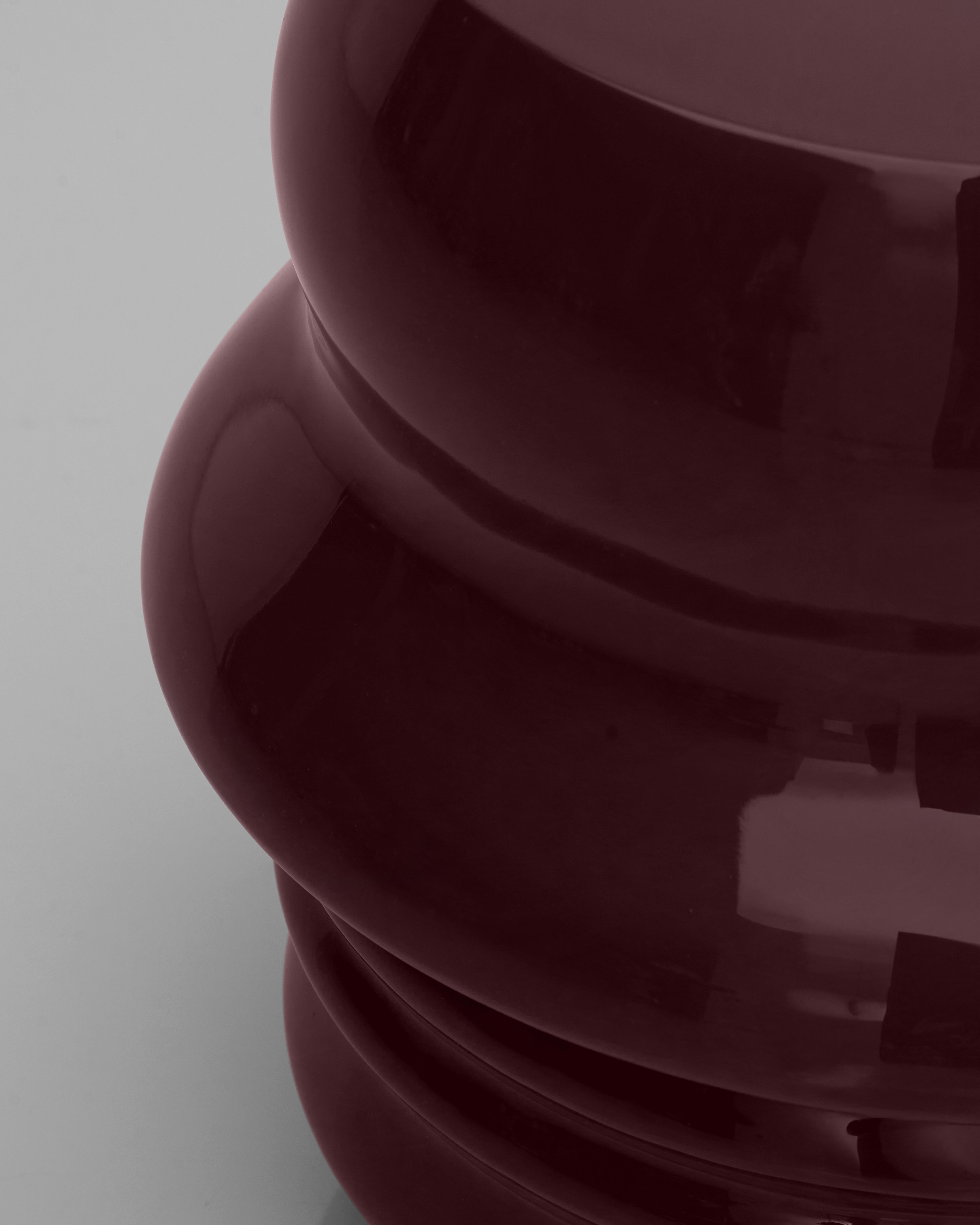 Close-up of a dark red or burgundy object with a reflective surface on a light gray background