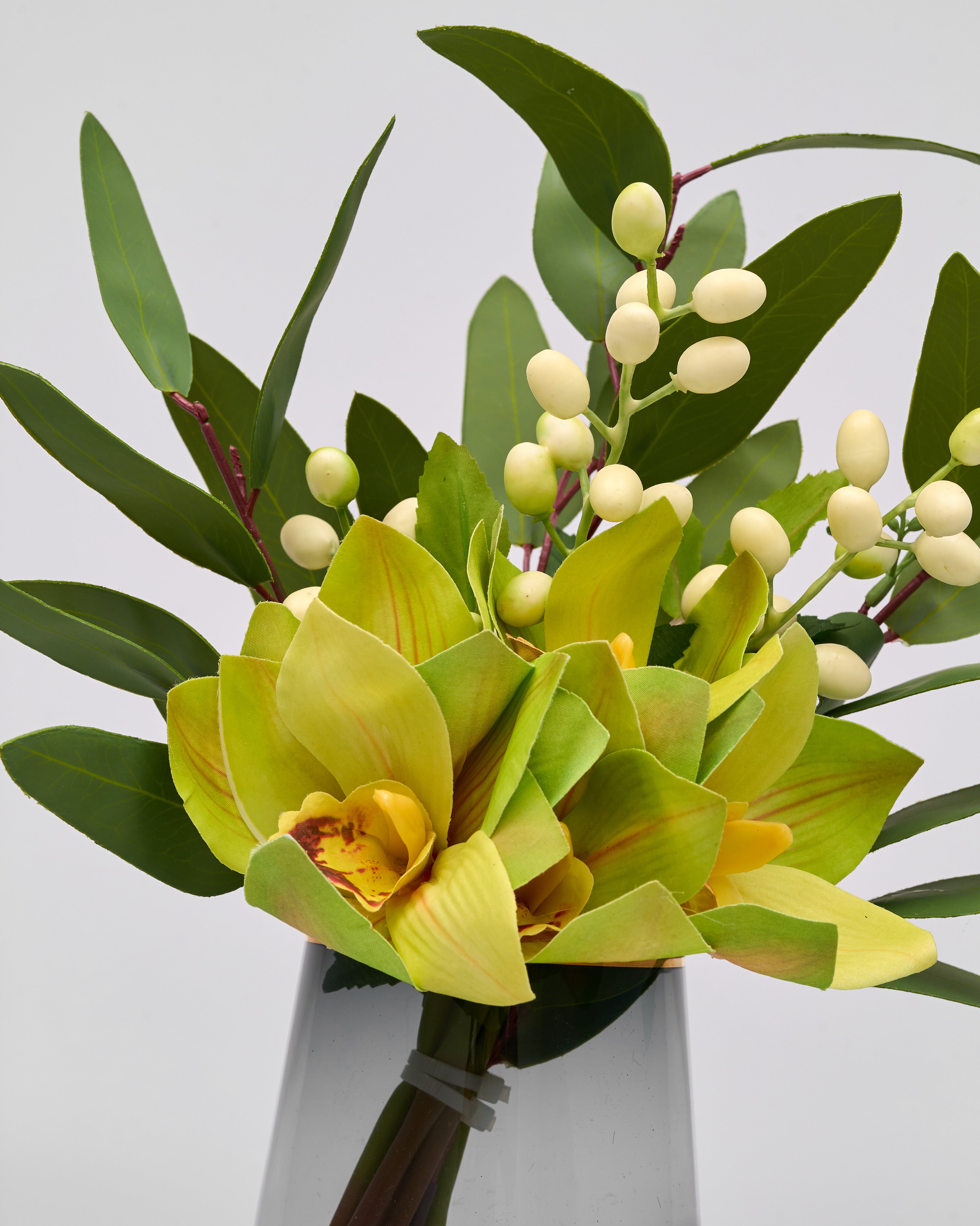 Bouquet of yellow orchids and green leaves on a light gray background
