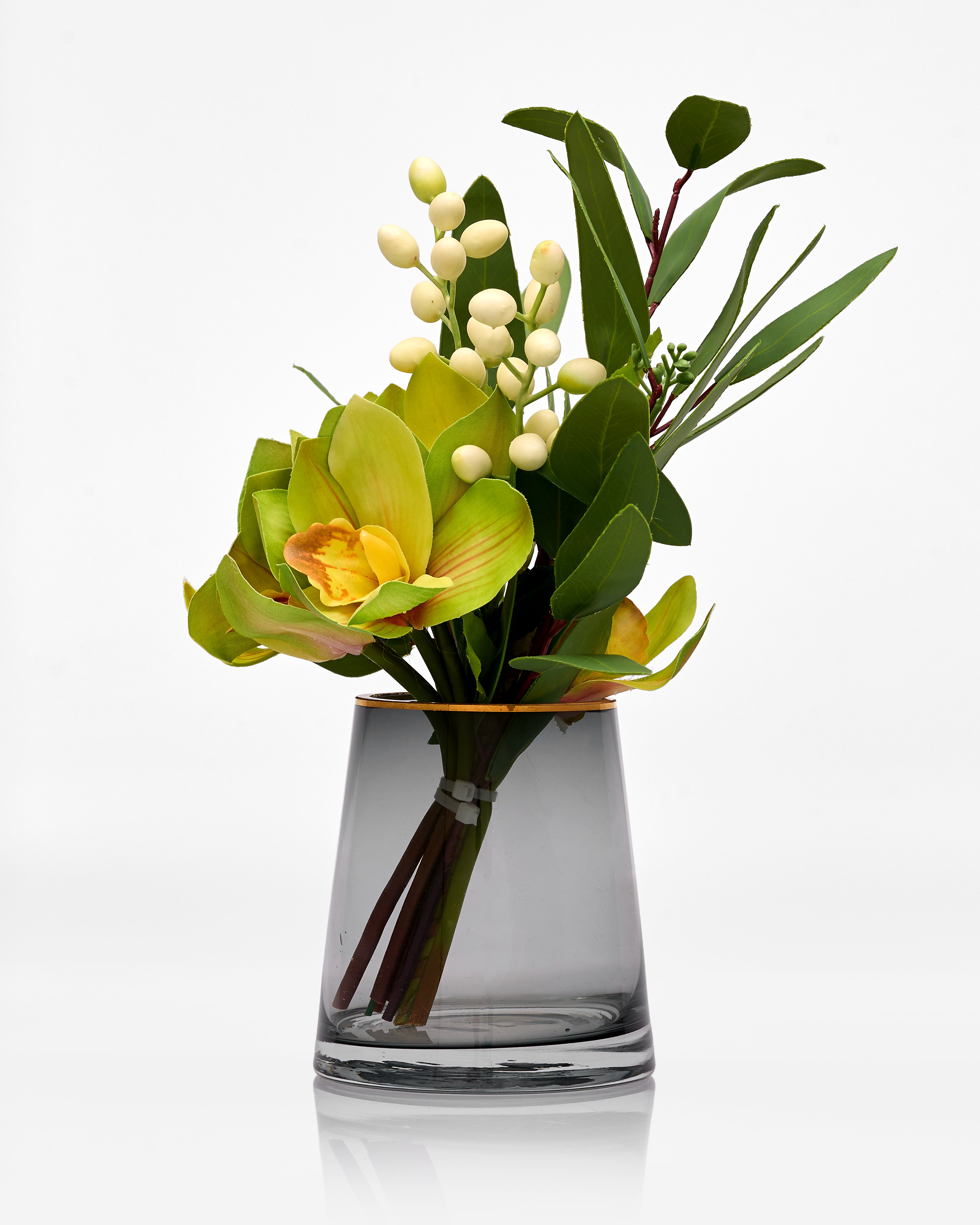 Artificial flower arrangement in a clear glass vase on a white background