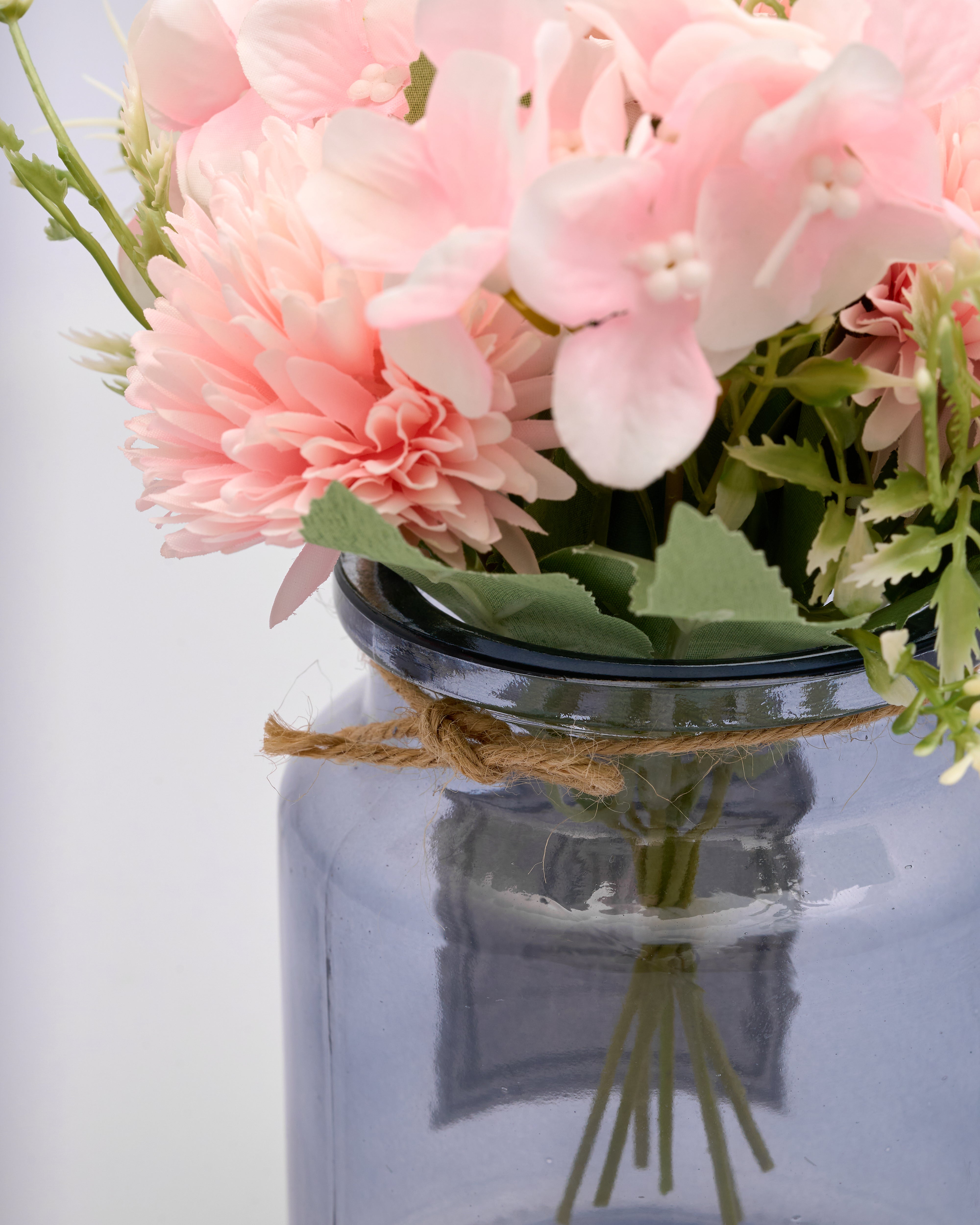 Pink flowers in a clear glass jar with a white background