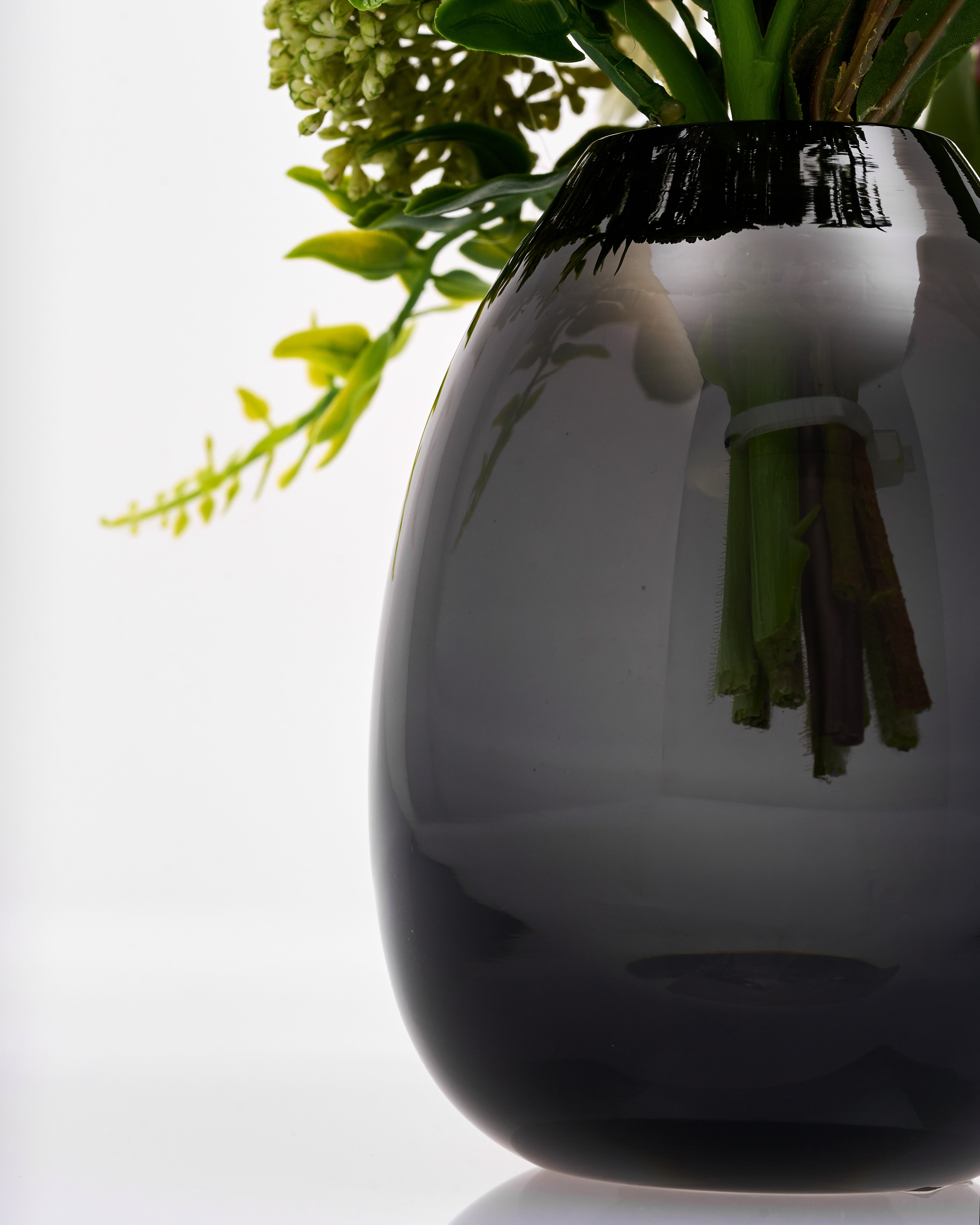 Black vase with greenery on a white background