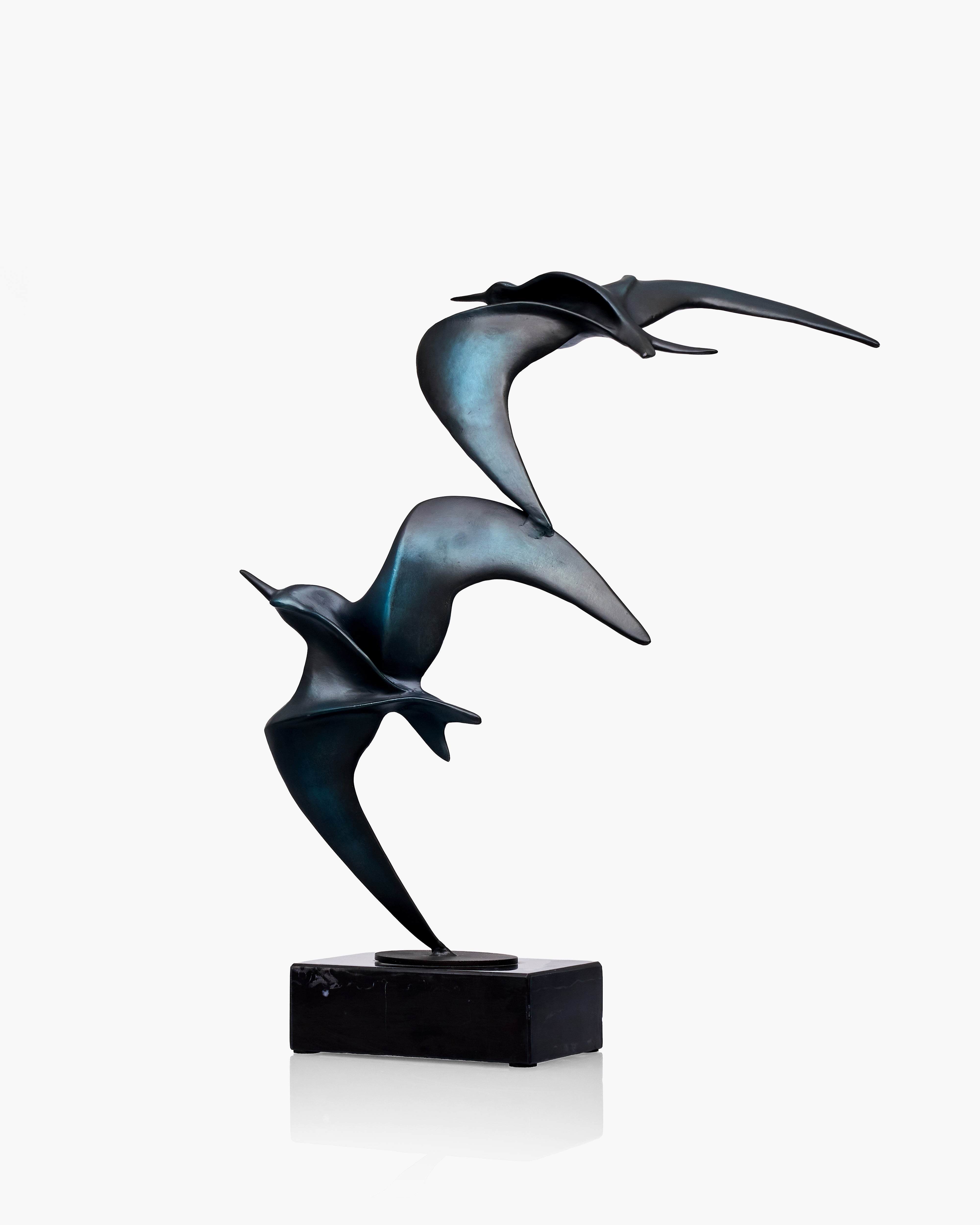 metal sculpture of two birds in flight on a white background