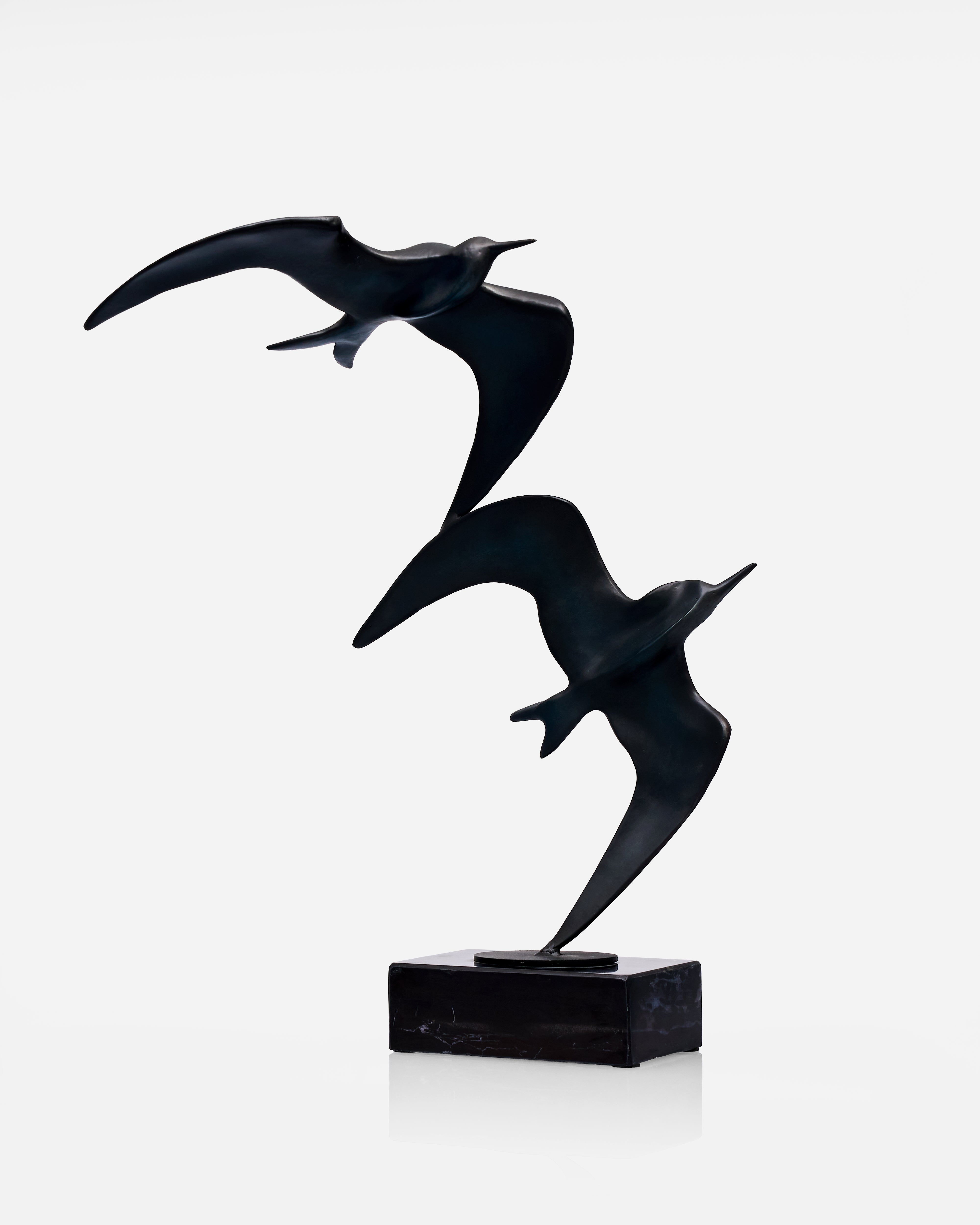 Black sculpture of two birds in flight on a white background