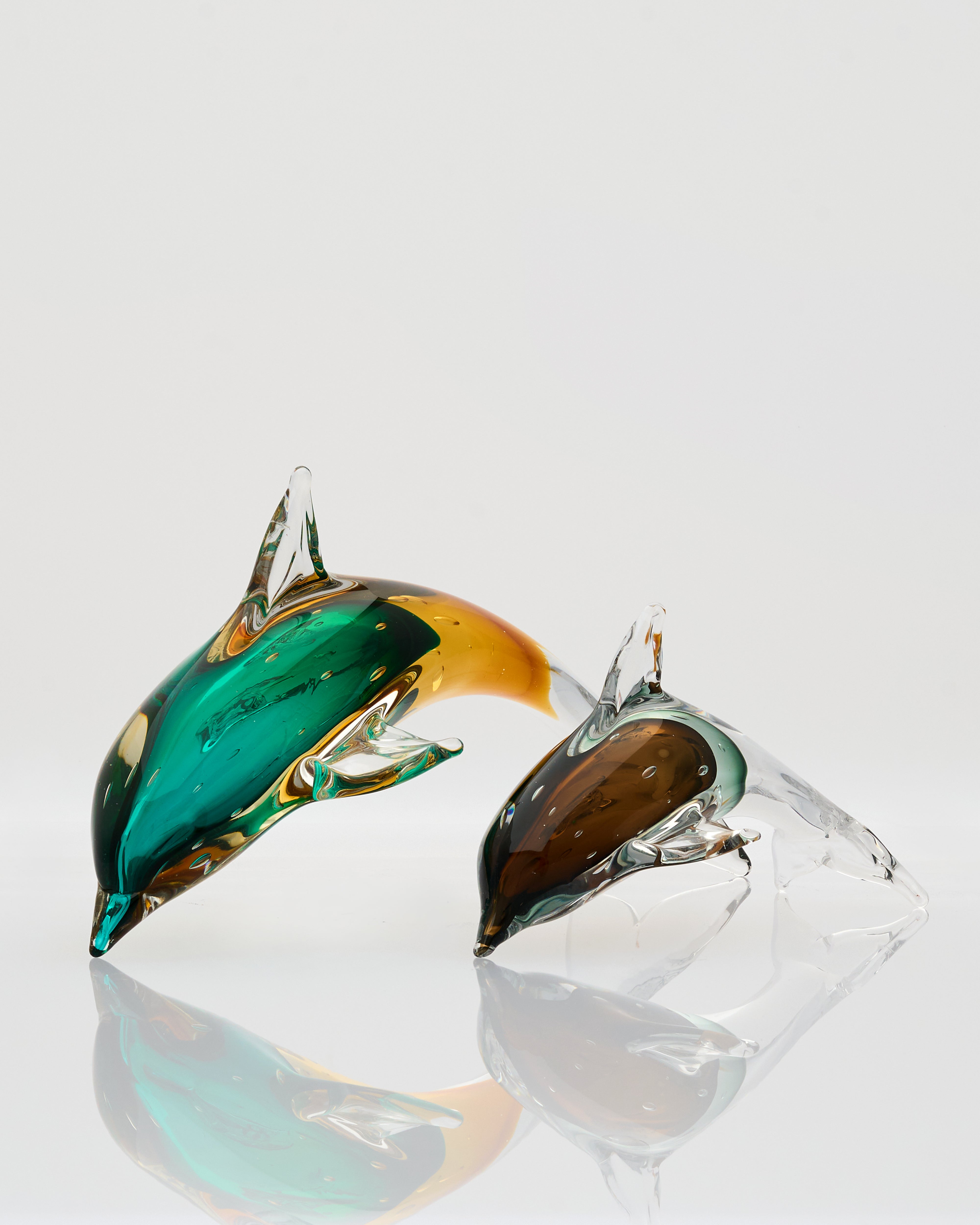 Glass dolphins on a clear stand with a white background