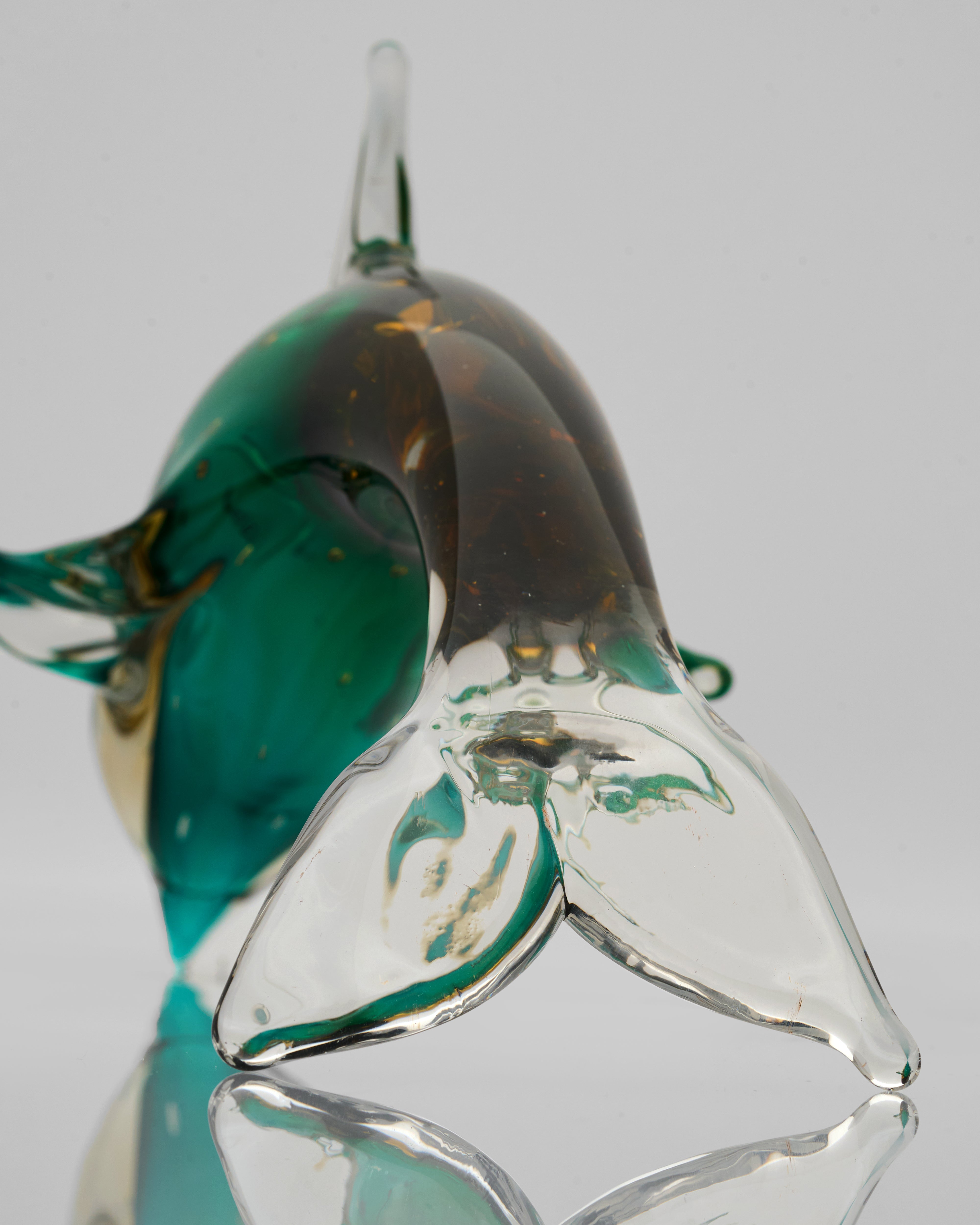 Glass sculpture of a fish with green and clear colors on a white background