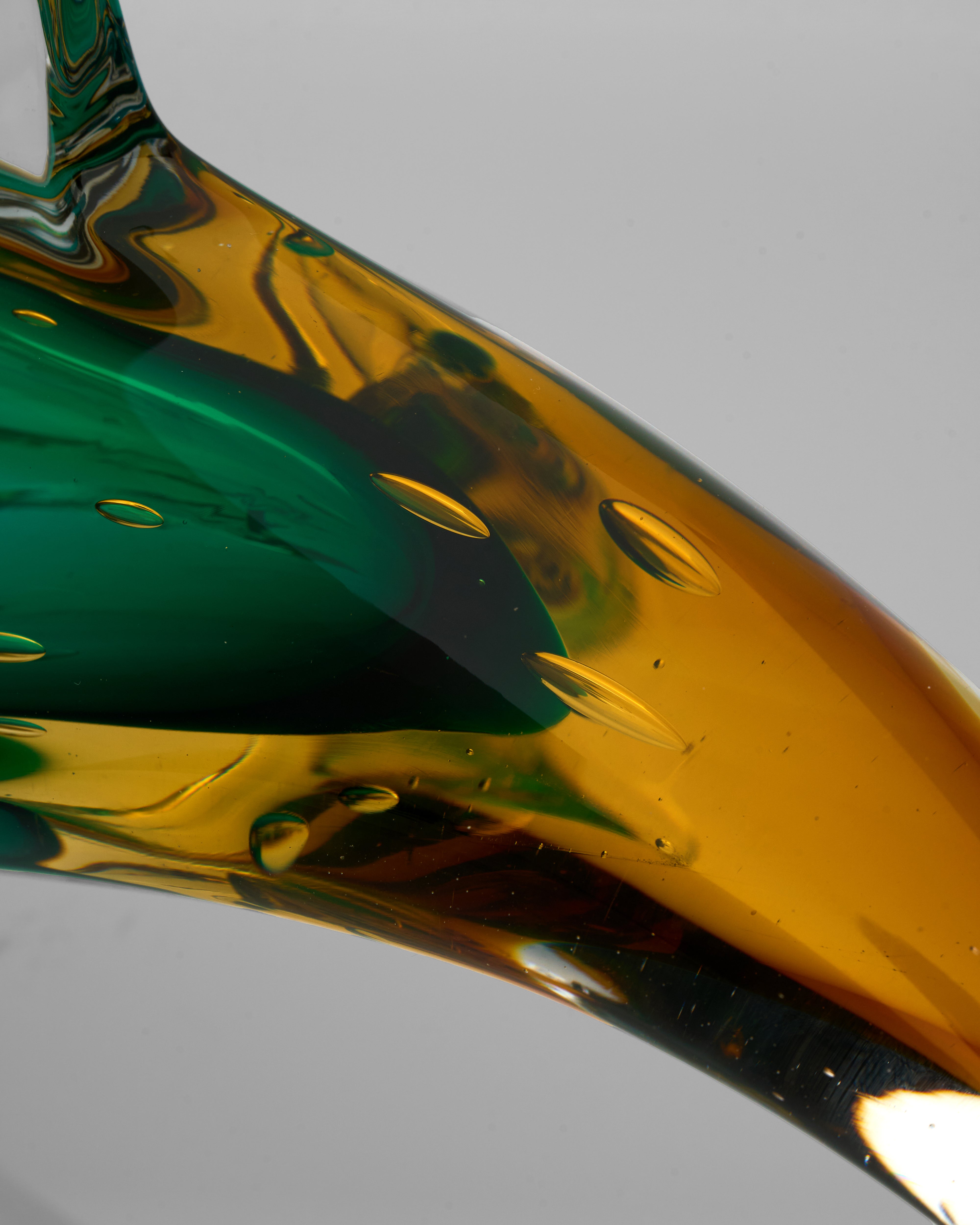 Close-up of a glass object with green and gold colors on a gray background