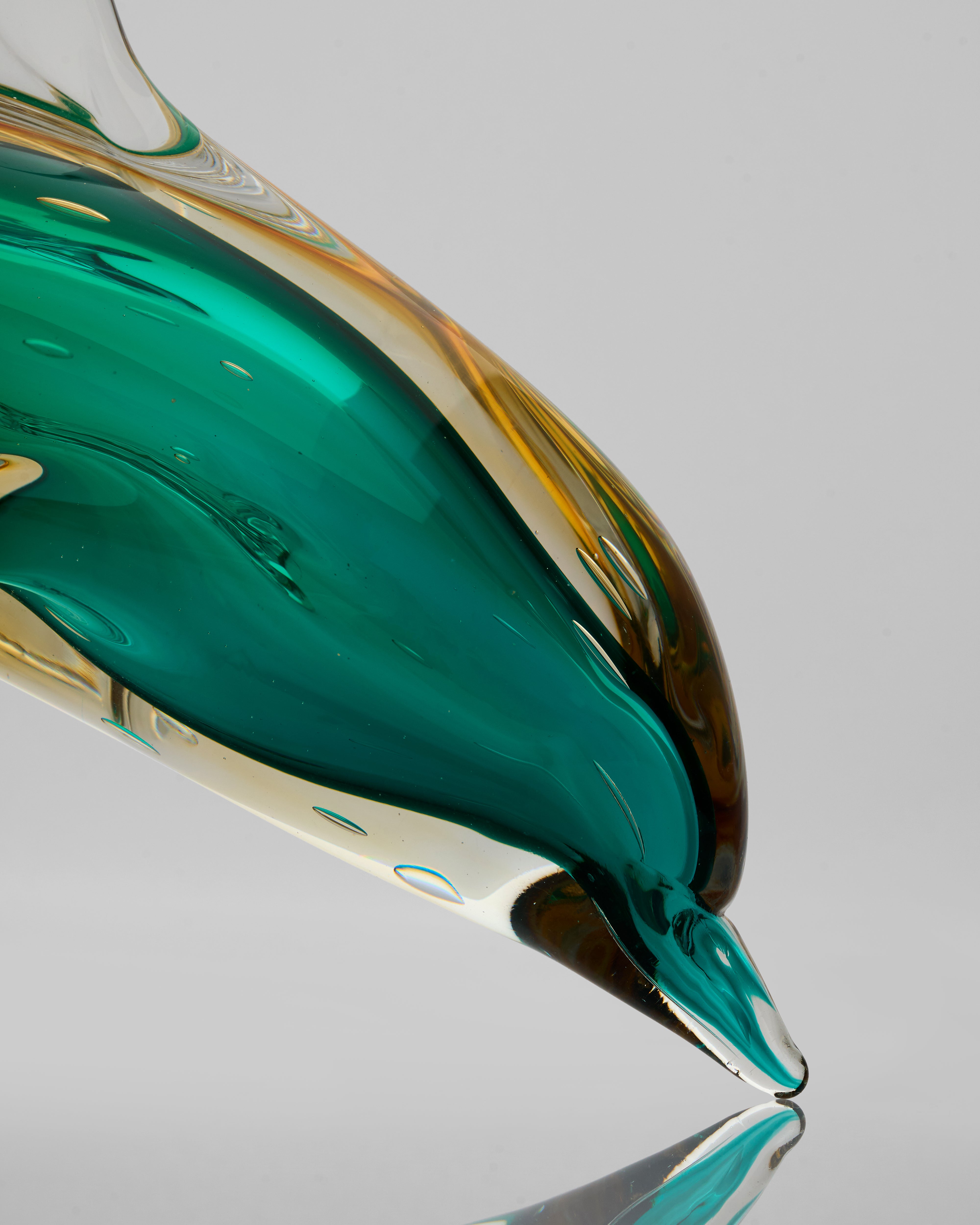 Close-up of a glass object with green and gold colors on a gray background