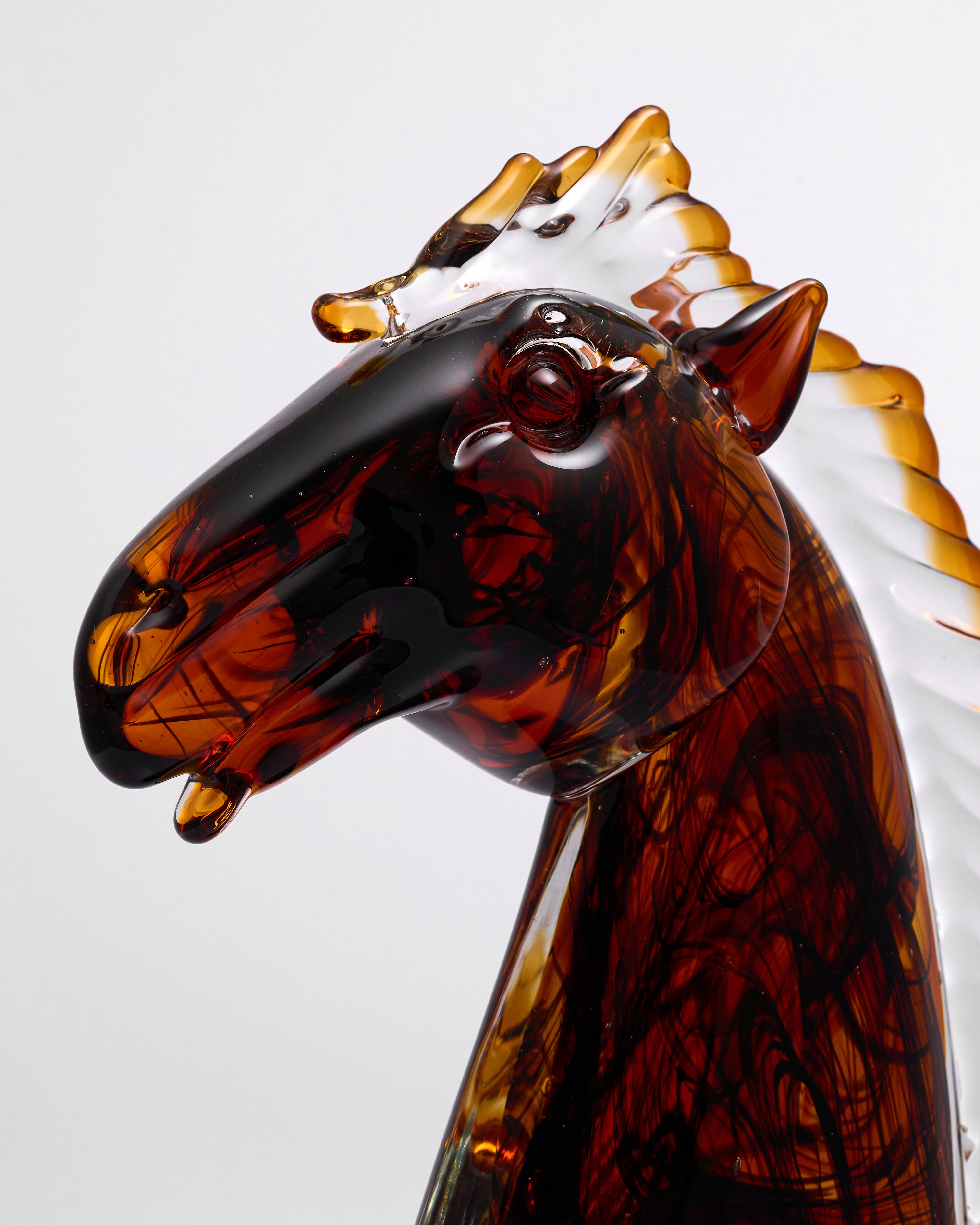 Glass horse sculpture with a tortoiseshell pattern on a white background