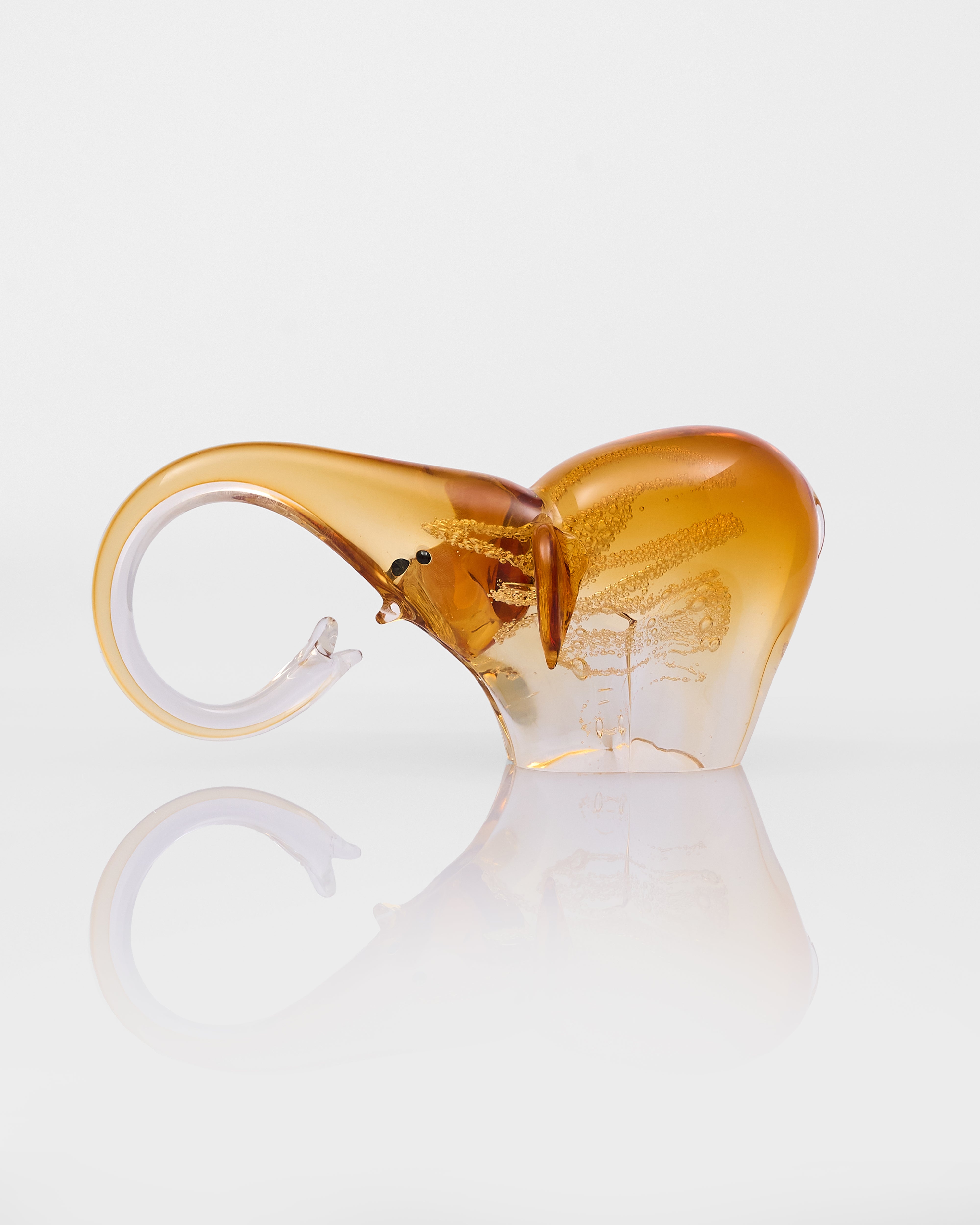 Glass sculpture of a stylized elephant with a gradient color effect on a white background
