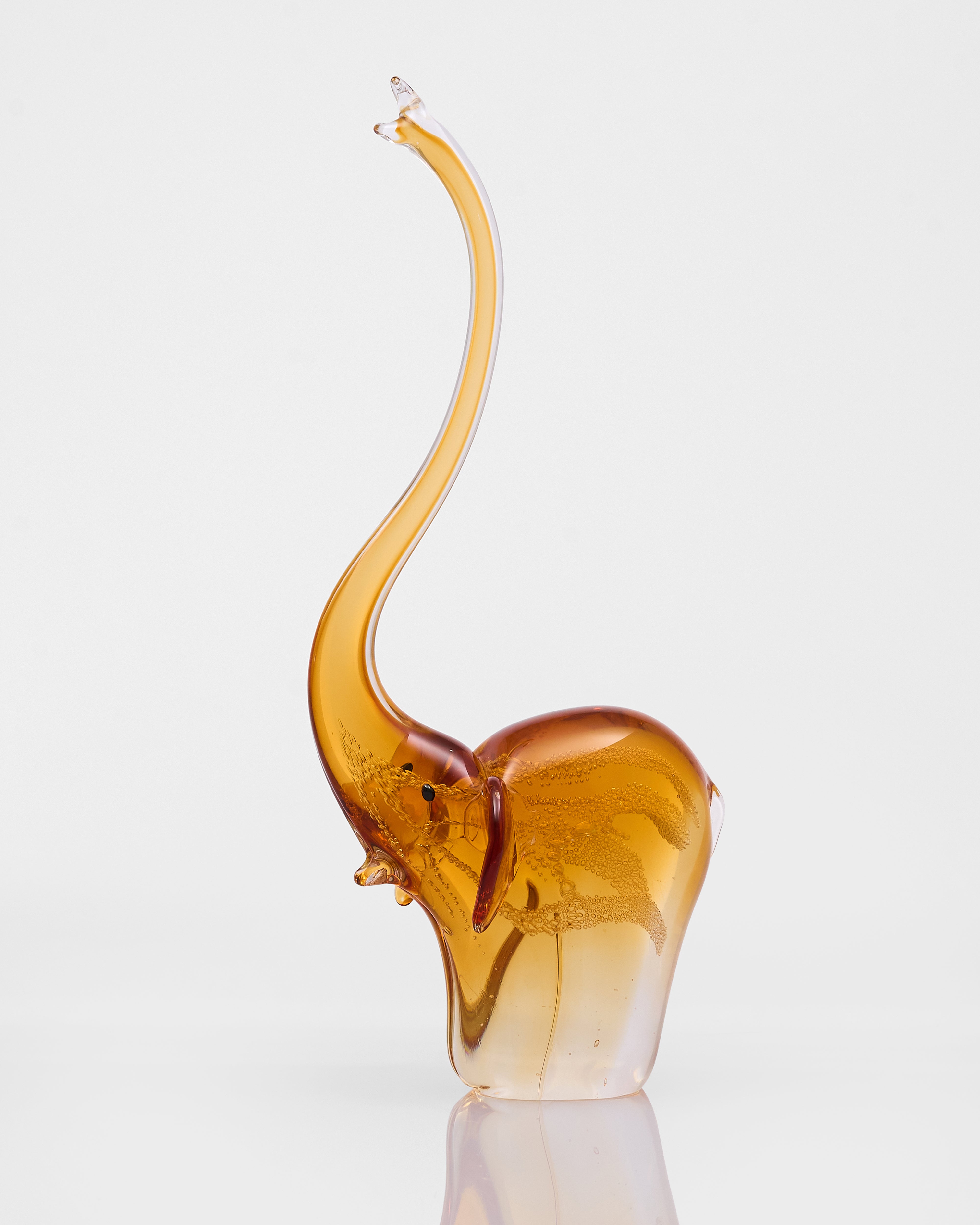 Glass sculpture of an elephant with a long trunk on a white background