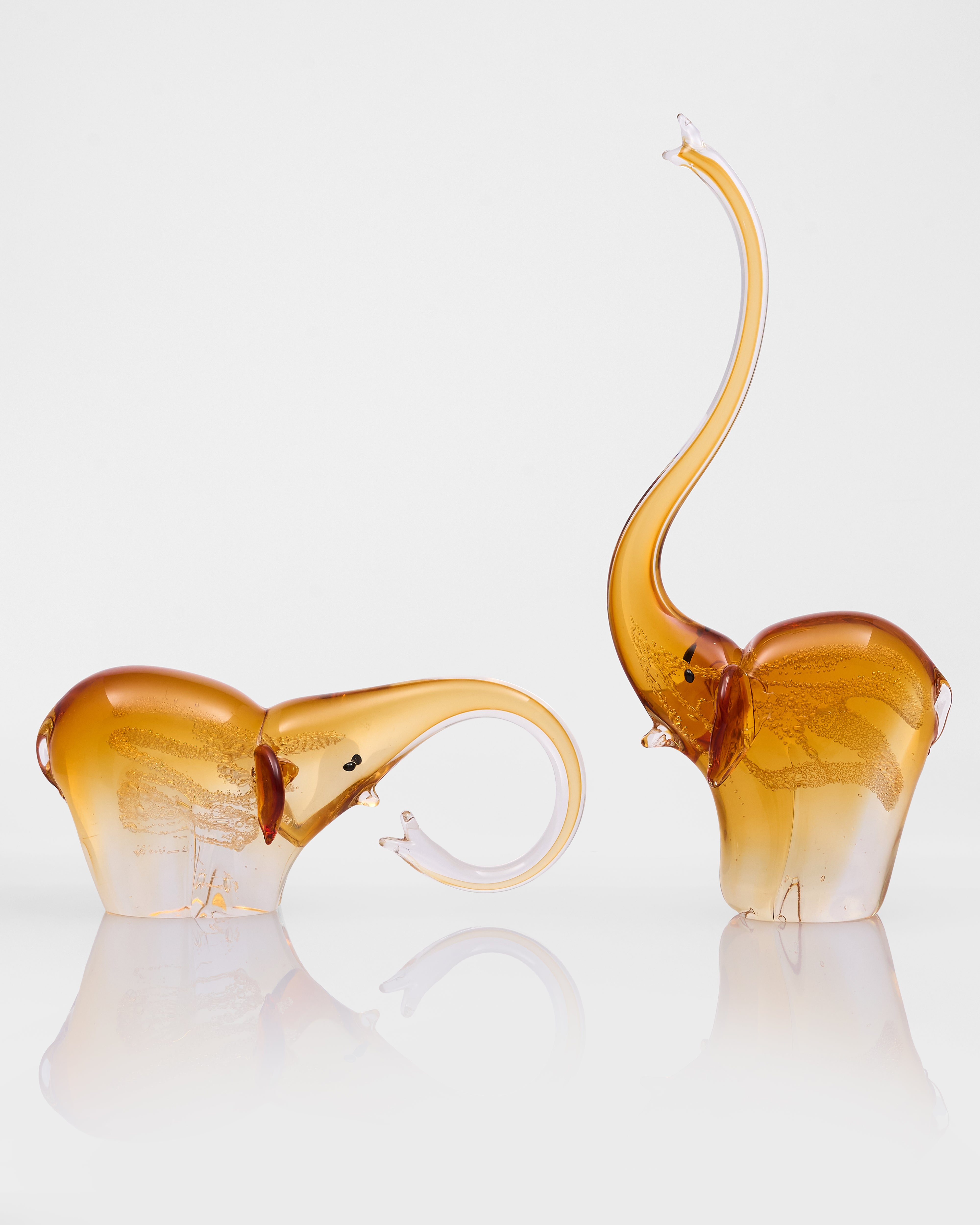Two amber-colored elephant-shaped objects on a white background